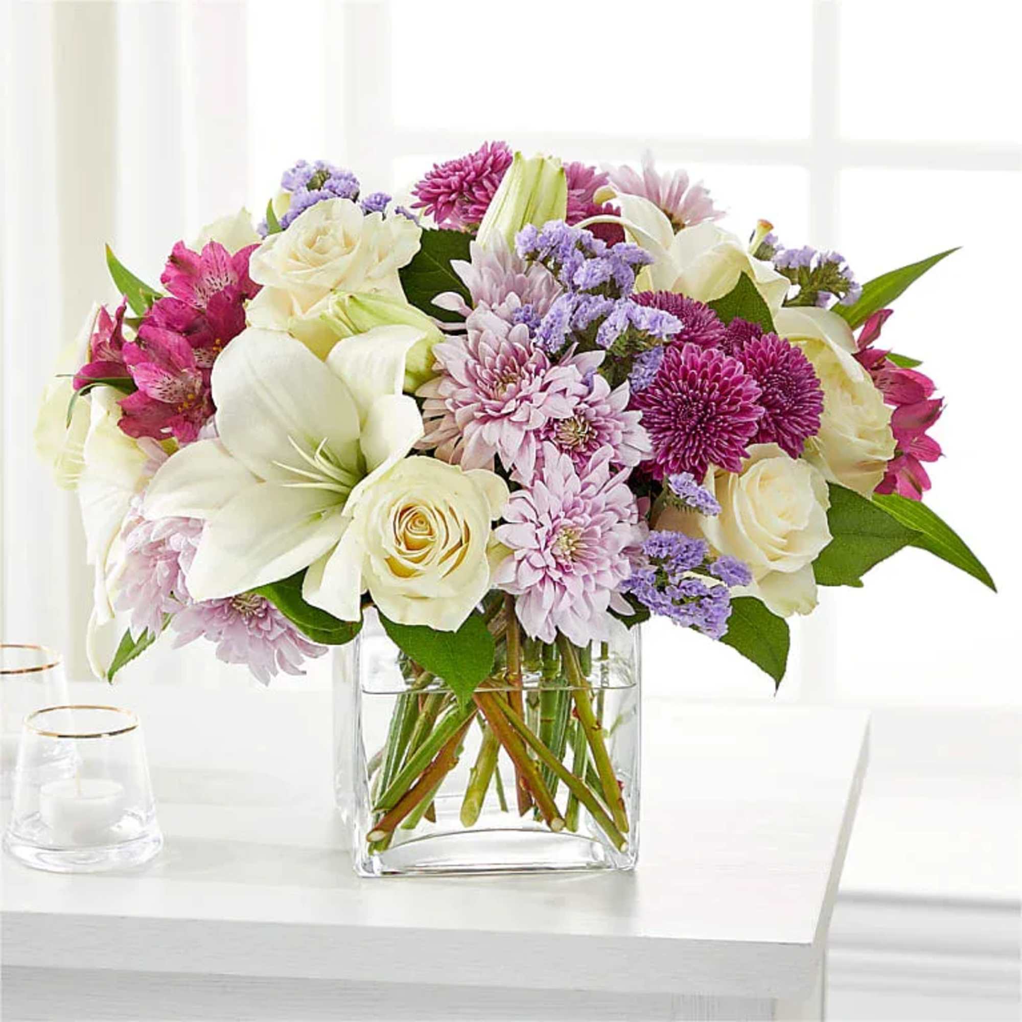 Mixed bouquet of white, pink, and purple flowers in a clear glass vase