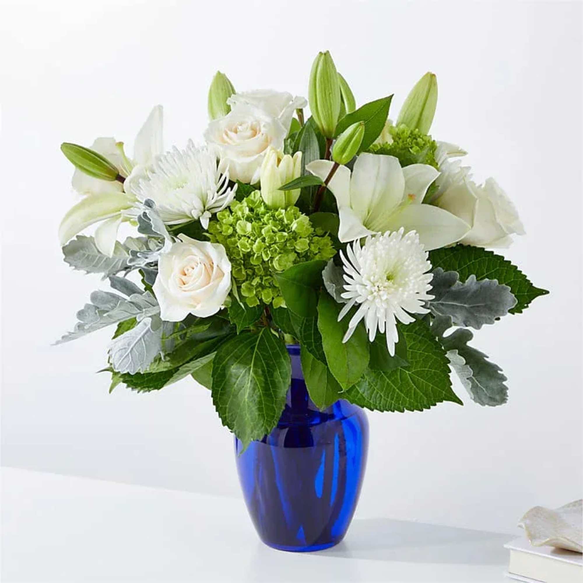 White lilies and roses in a blue glass vase