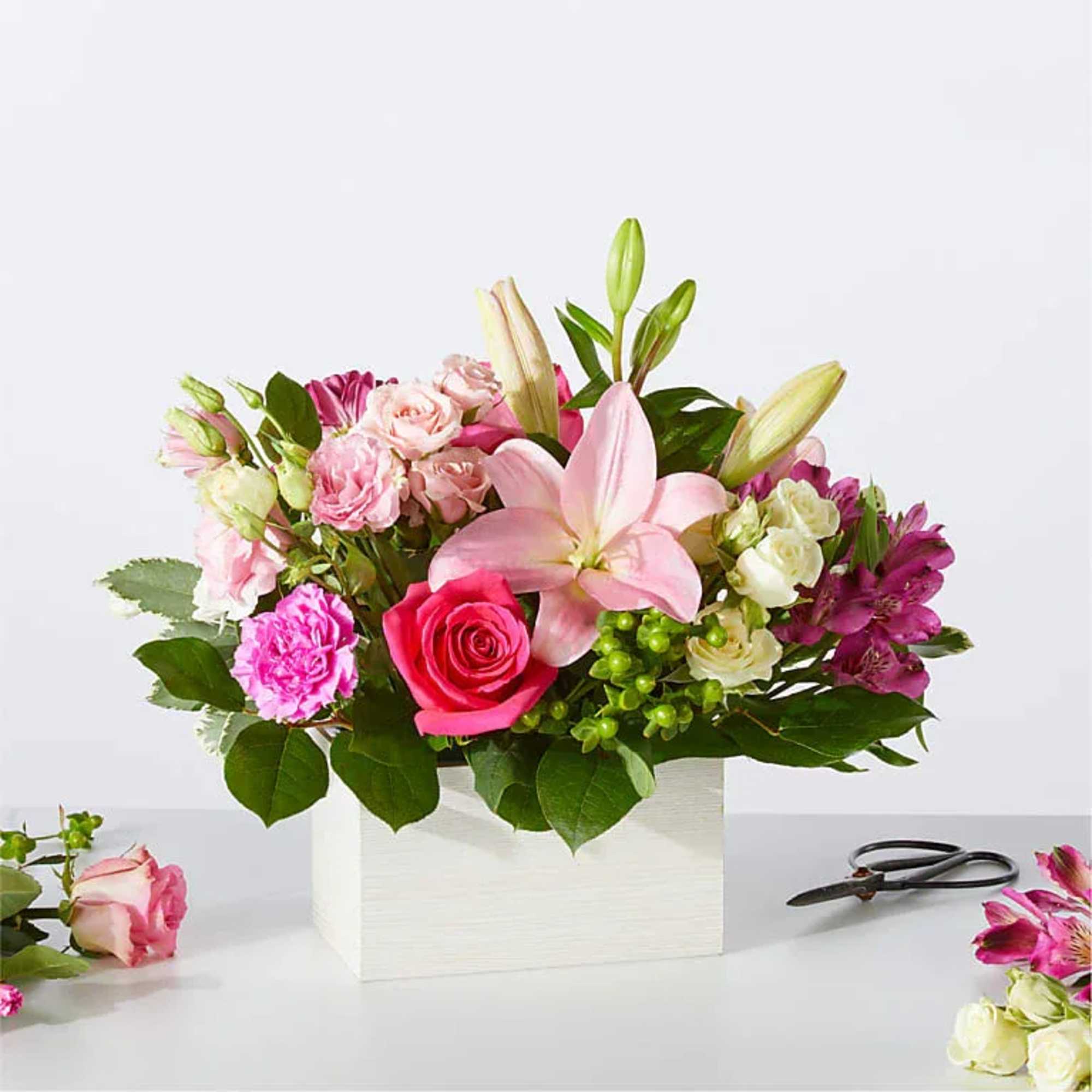 Pink lily and rose arrangement in a white square vase