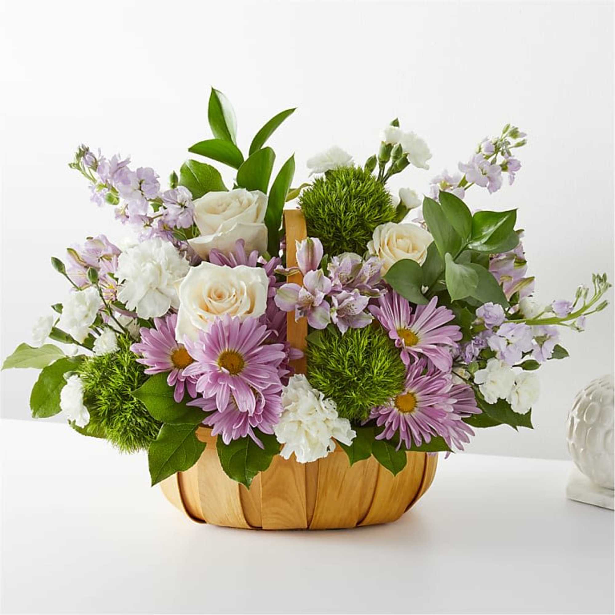 Basket arrangement of white roses, purple daisies, and green pom-pom flowers