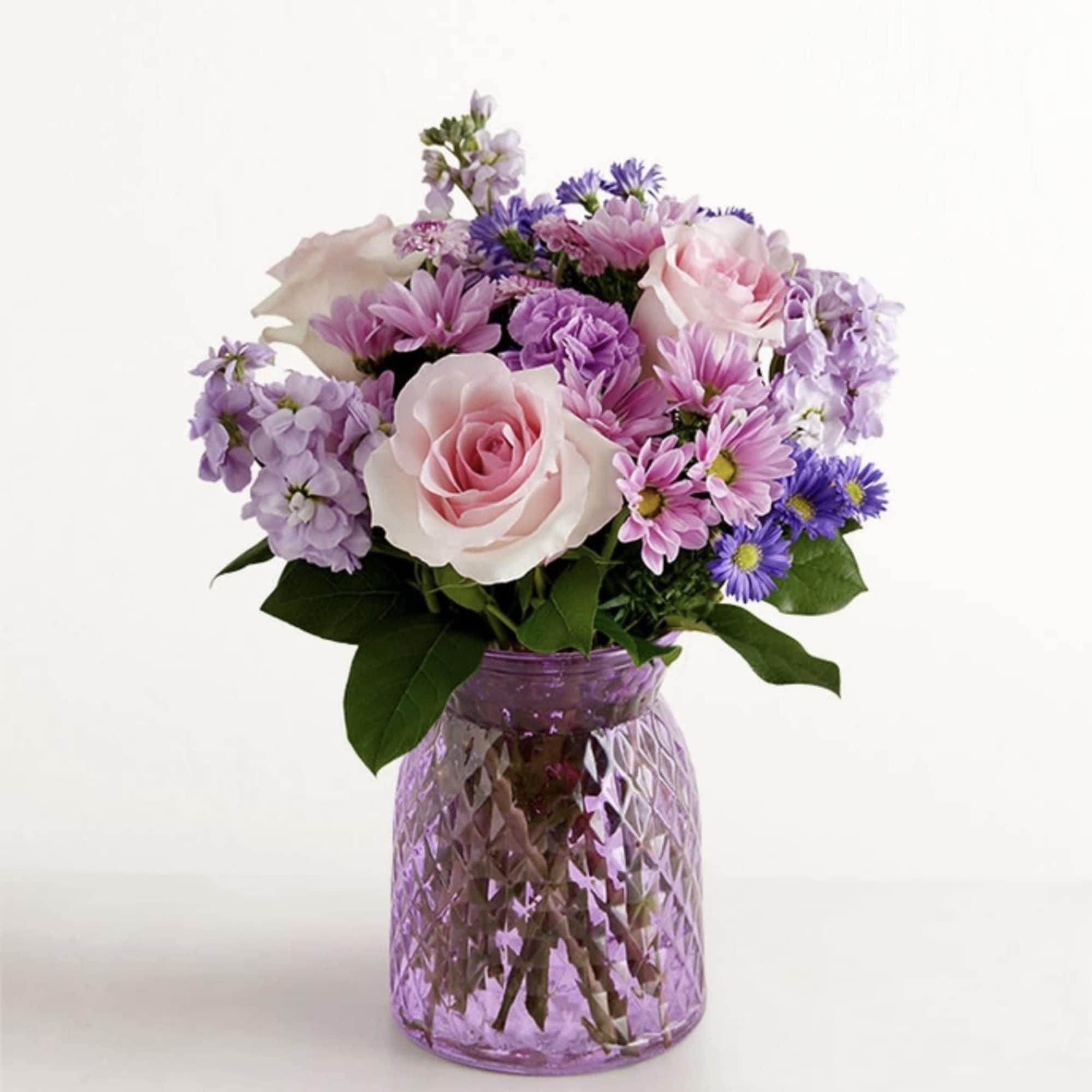 Pink and lavender mixed bouquet in a purple glass vase