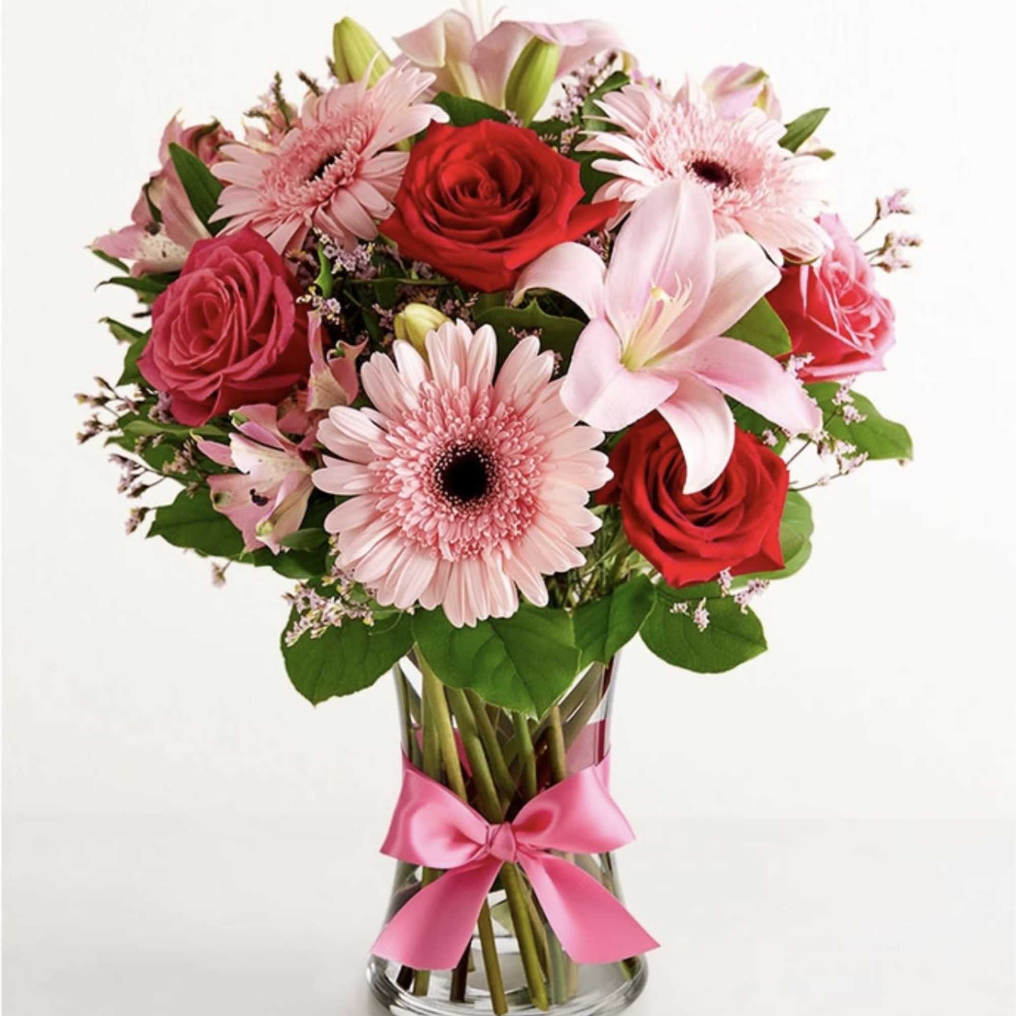 Pink and red flower bouquet in a glass vase with a pink ribbon