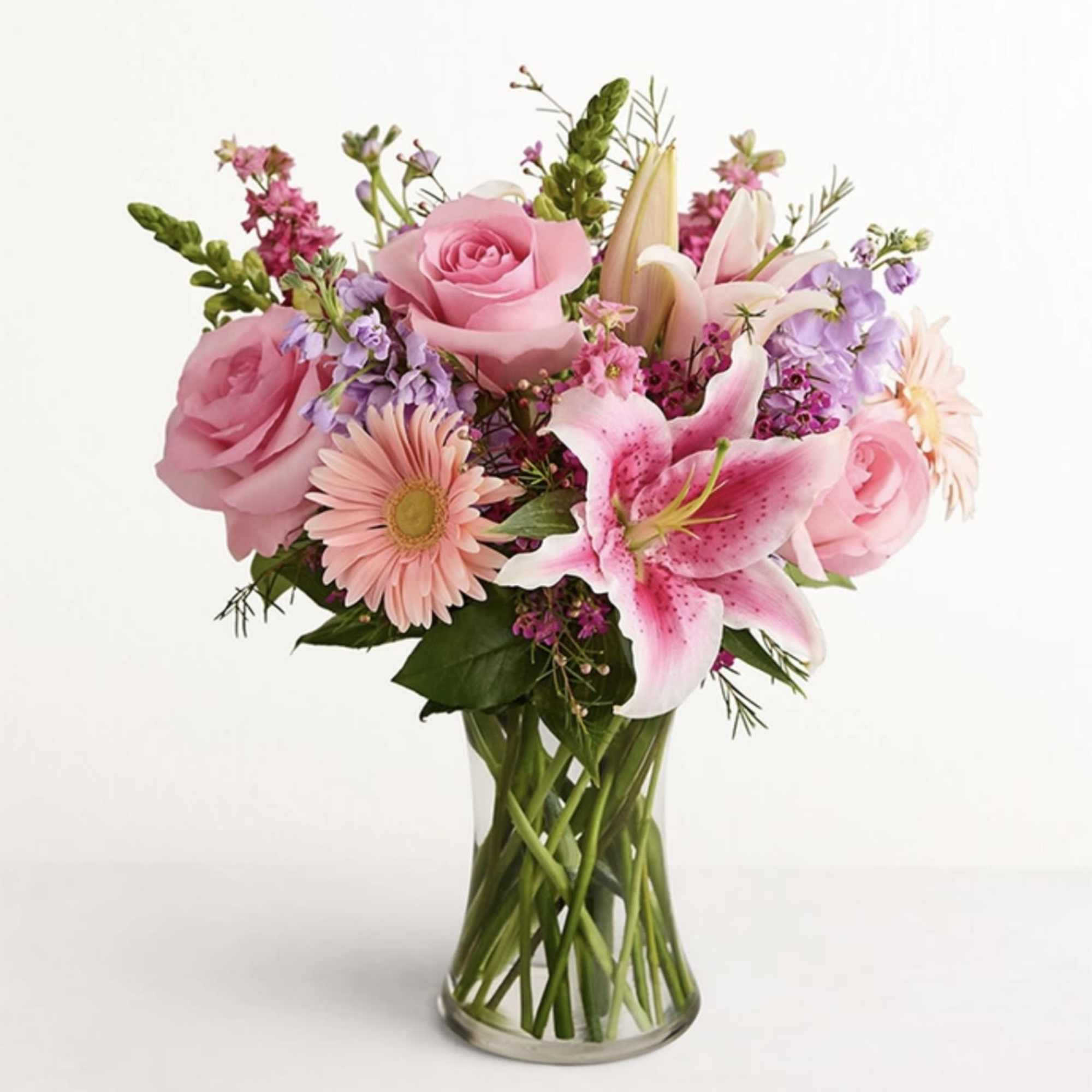 Pink roses and lilies arranged in a clear glass vase