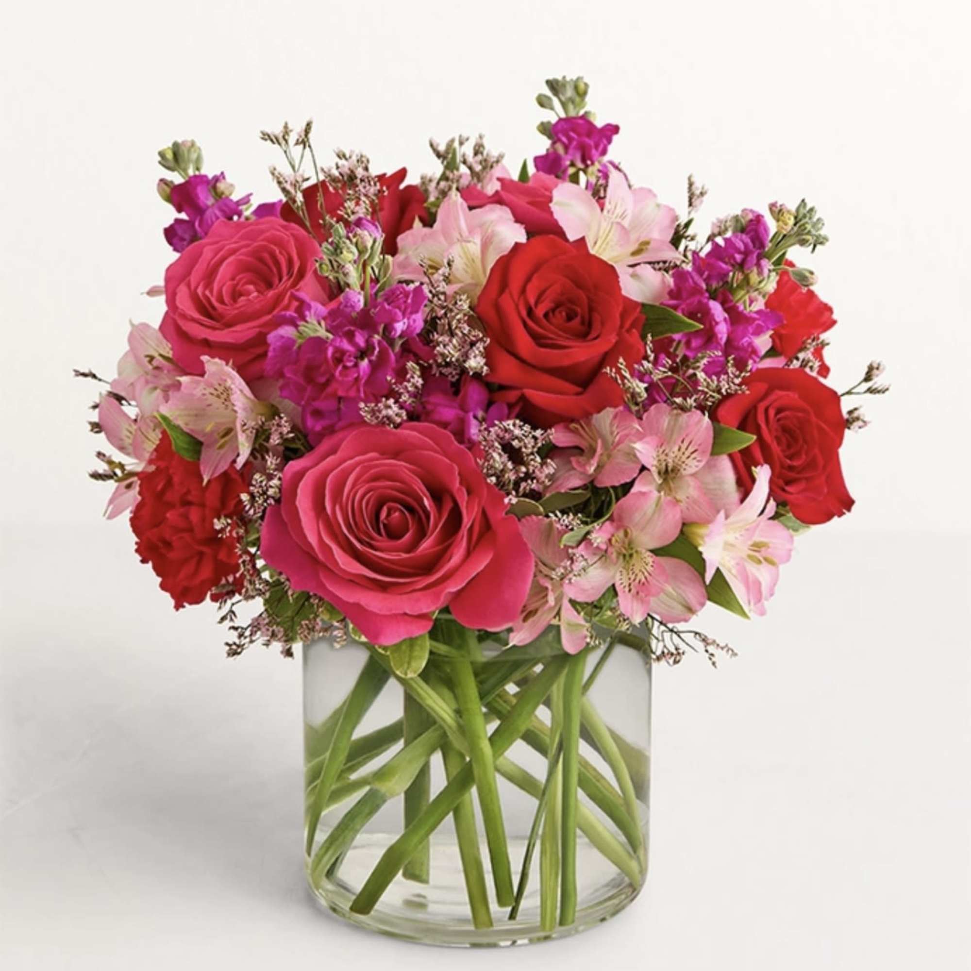 Pink and red roses with pale pink lilies in a clear glass vase
