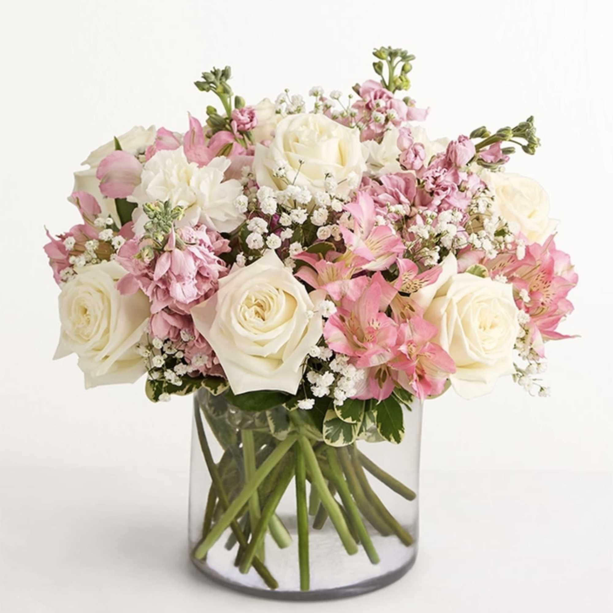 Pink and white roses arranged in a clear glass vase