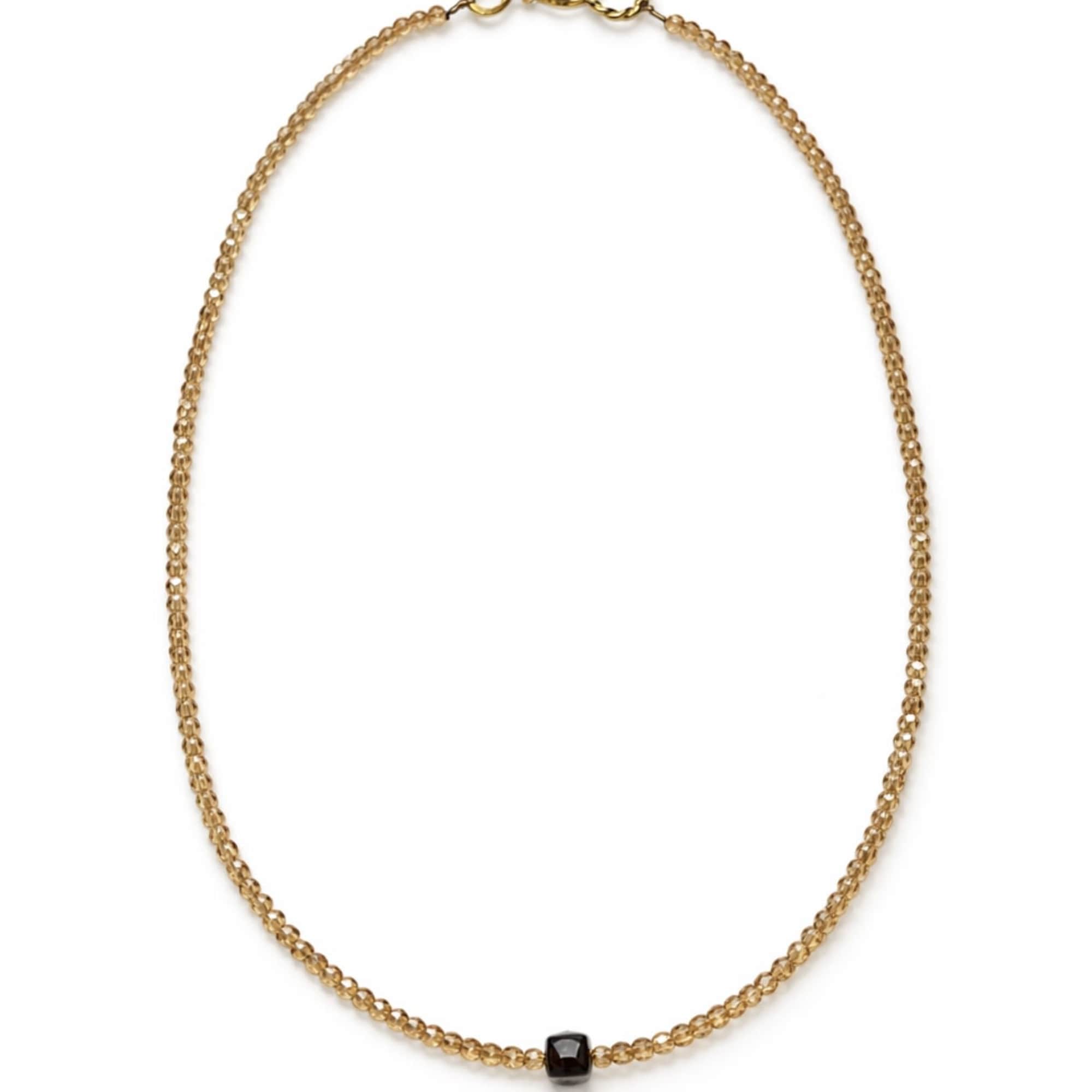 Gold beaded necklace with a small black pendant on a white background