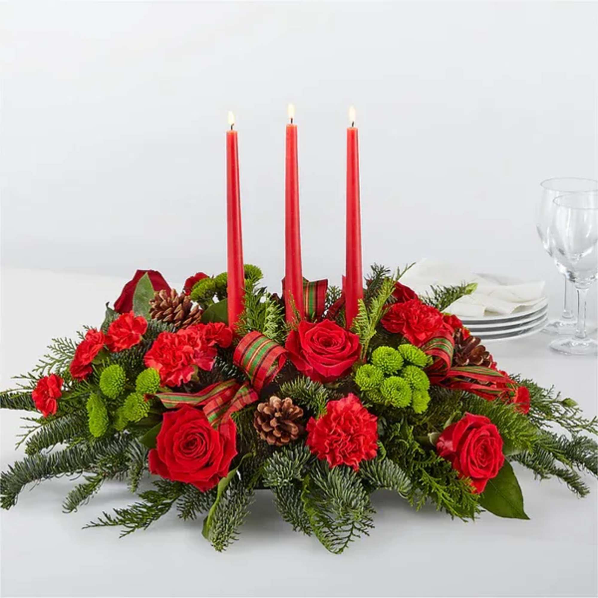 Red floral centerpiece with three lit taper candles