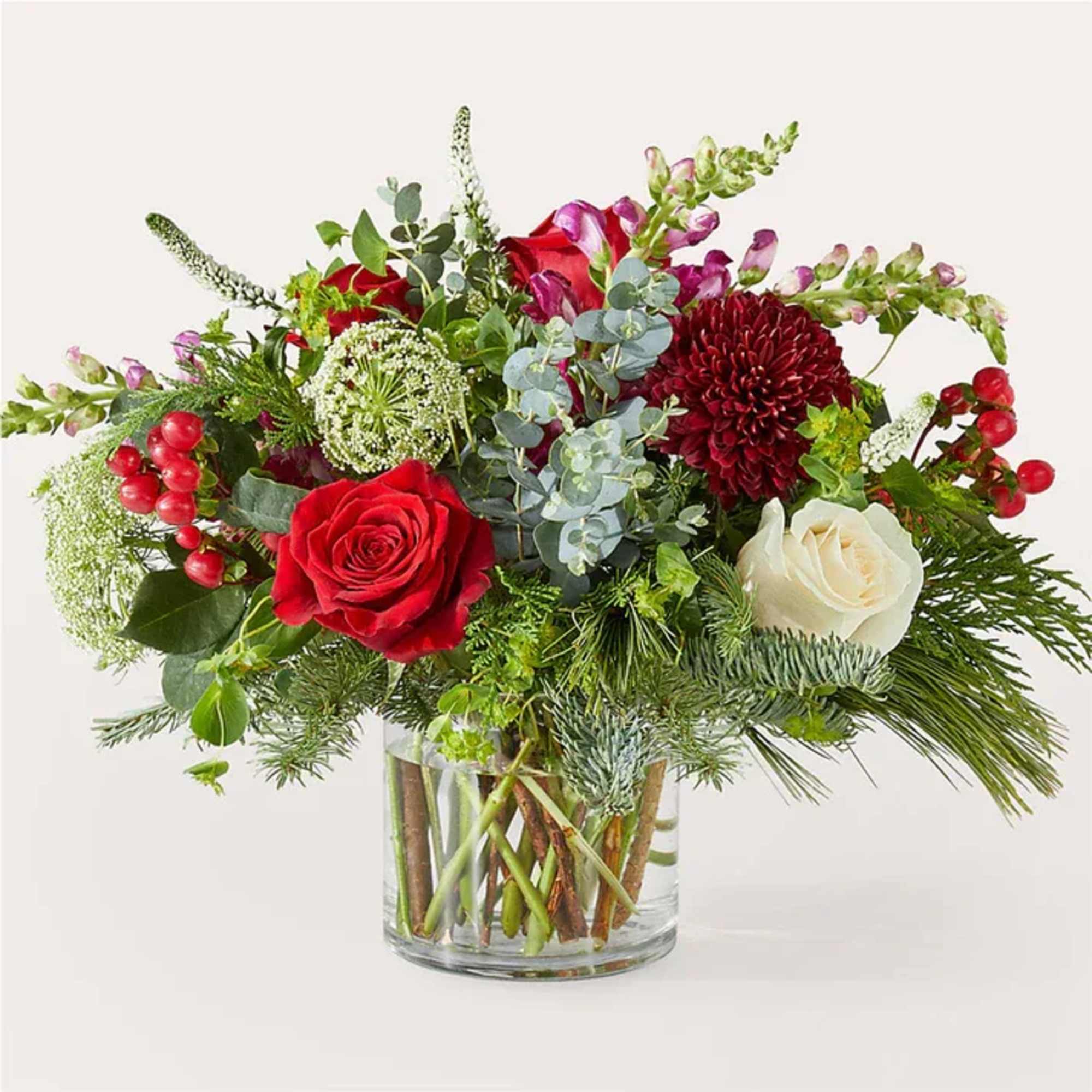 Red and white roses in a clear glass vase with mixed greenery