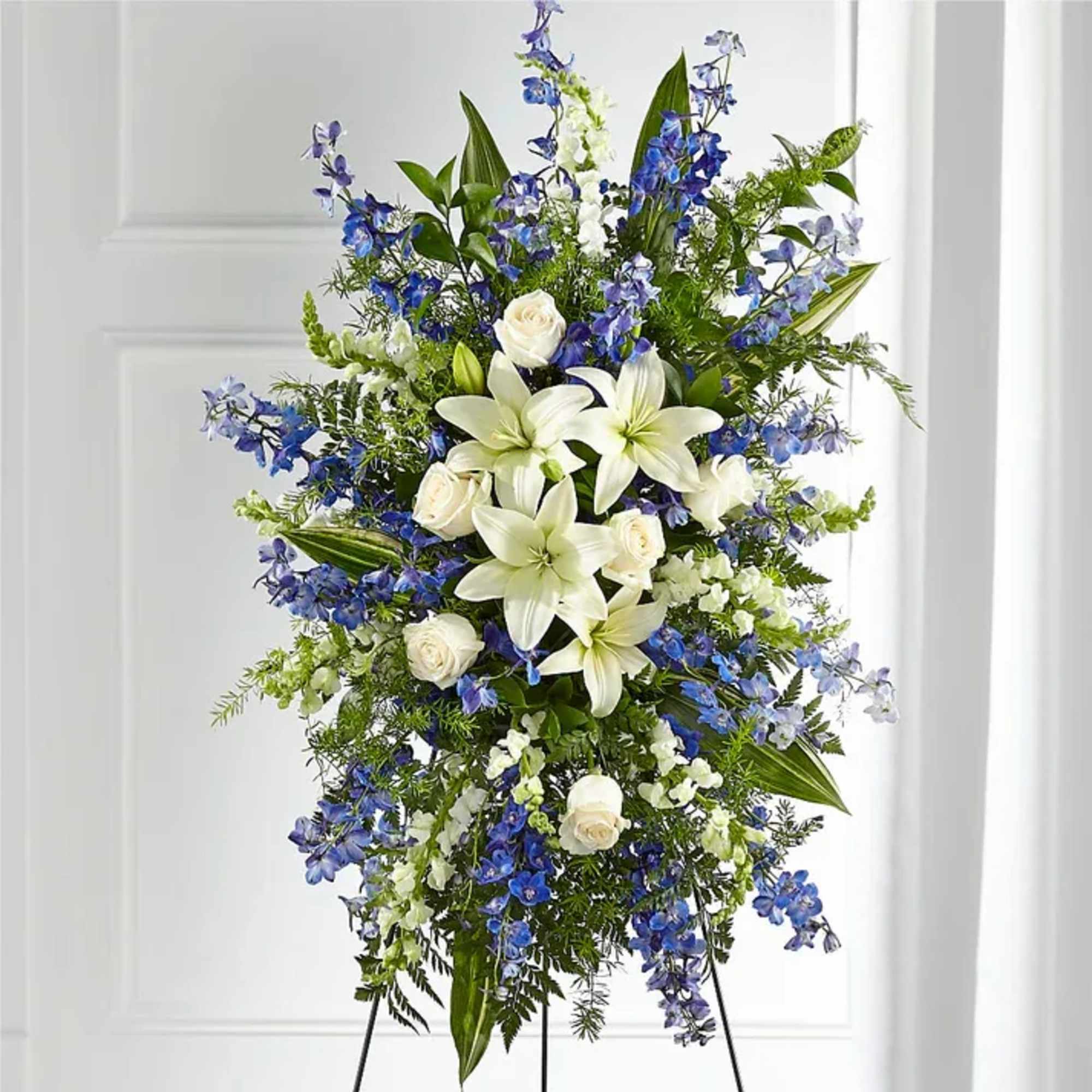 Tall standing spray of white lilies and blue flowers