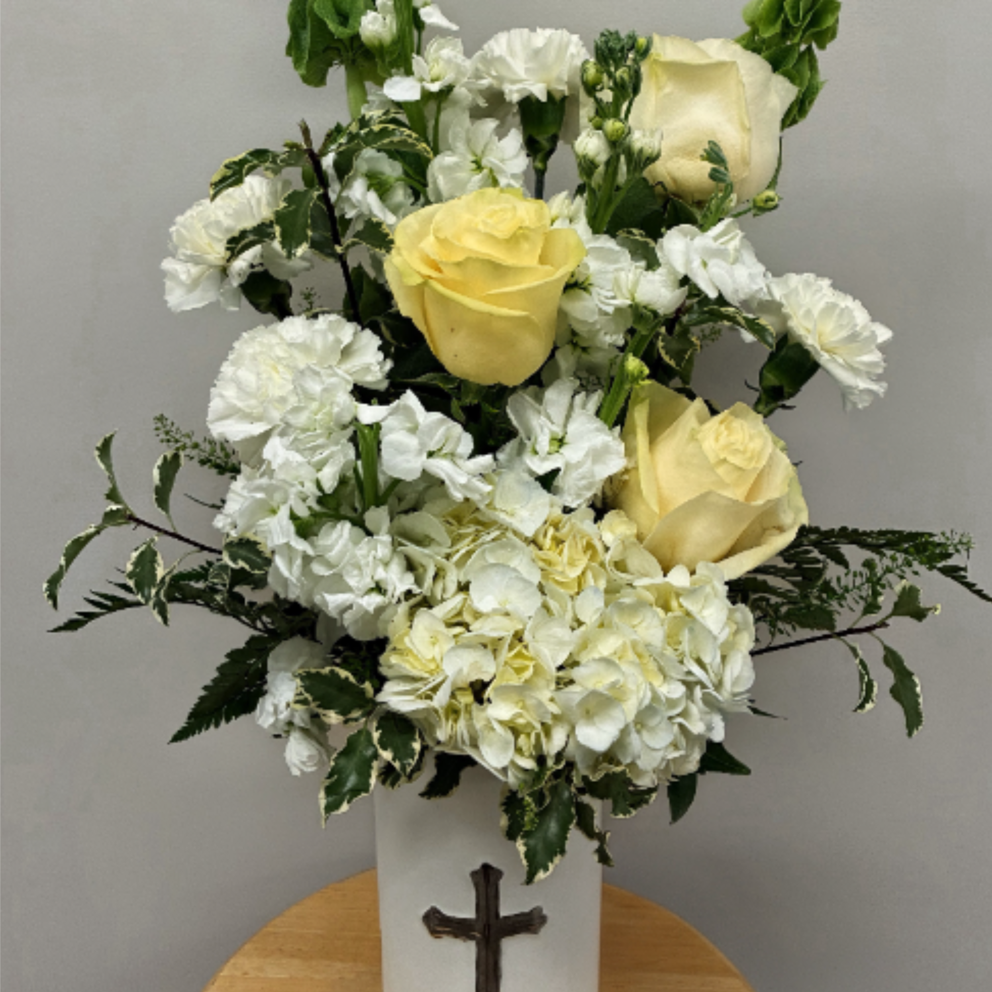 Cream roses tucked among clusters of white carnations and a generous spray