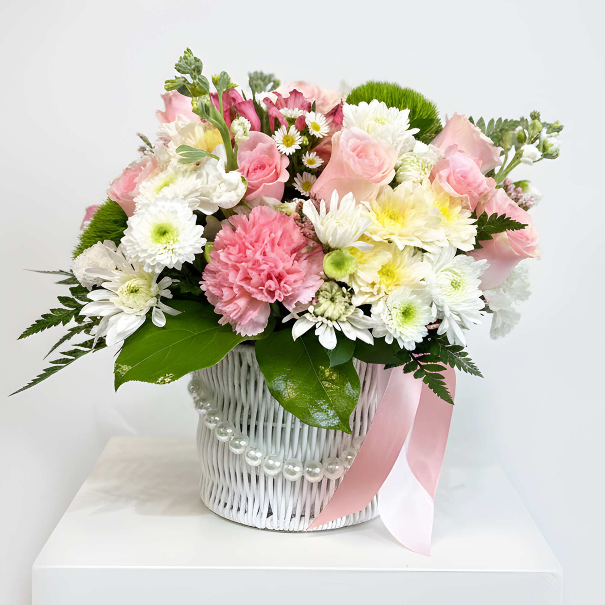 Pink and white mixed bouquet in a white basket with a pink ribbon