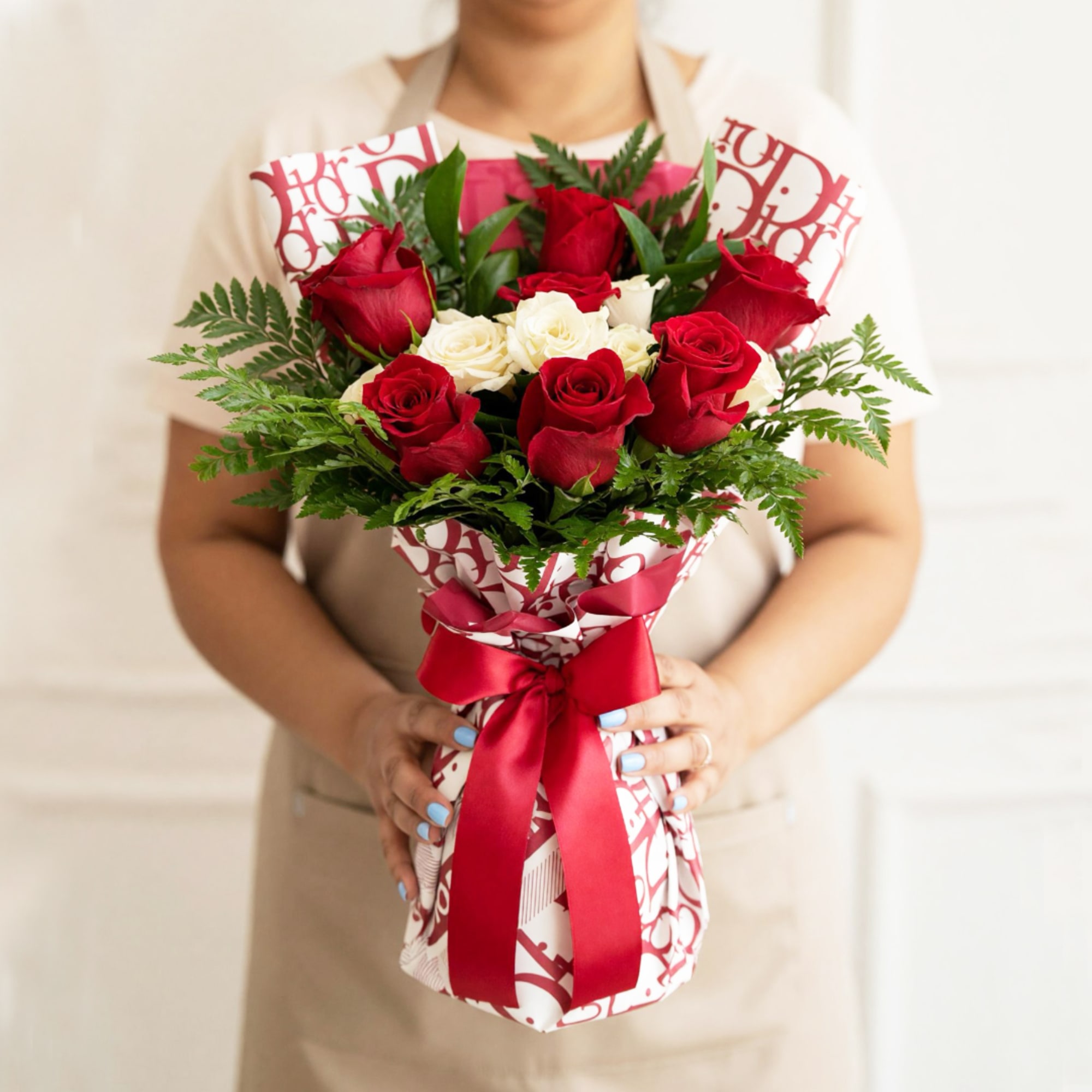 Bouquet of red and white roses wrapped in patterned paper with a red ribbon