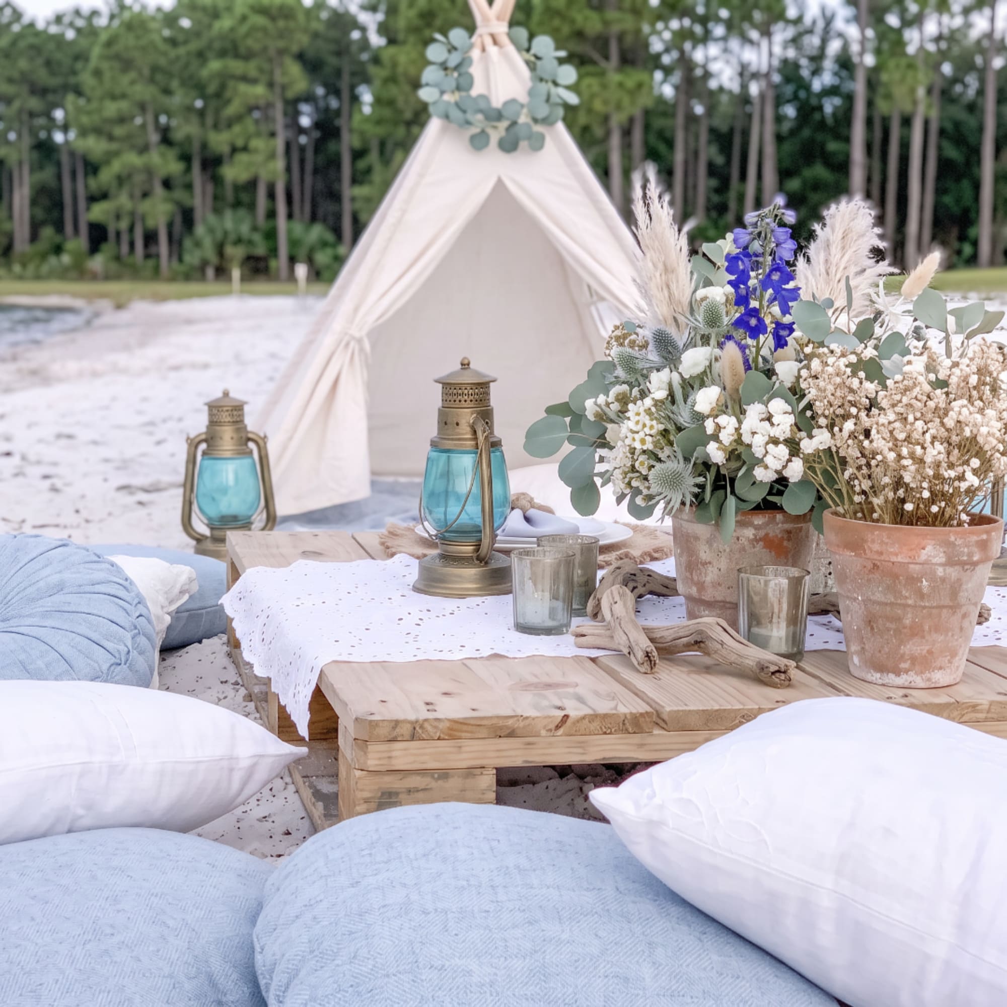 Boho outdoor table with a white floral arrangement and blue lanterns