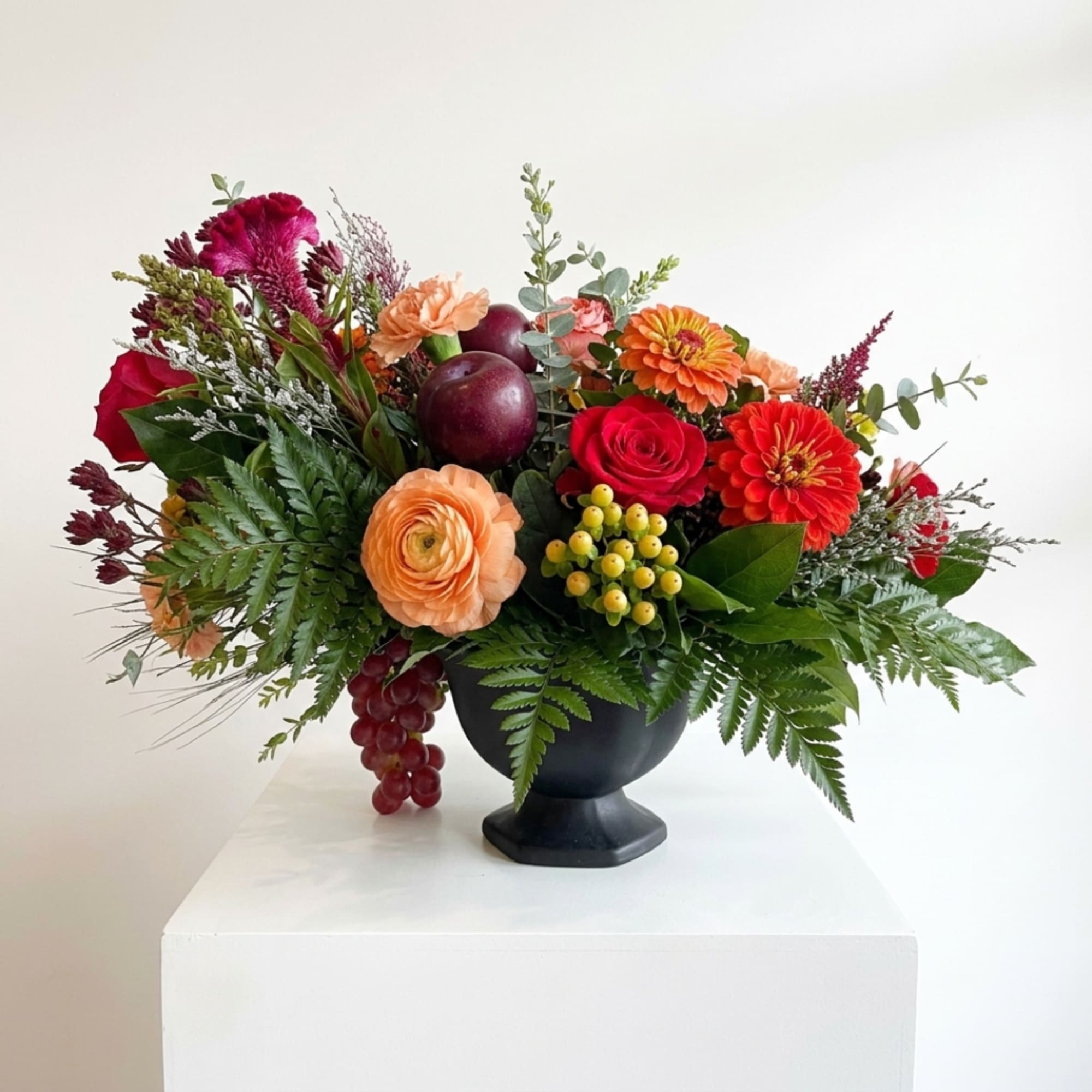 Mixed bouquet in a black urn with red, orange, and peach flowers