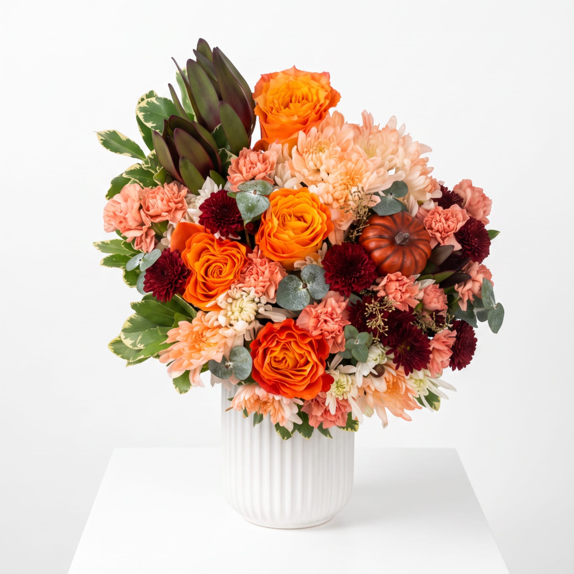 Bouquet of orange and peach flowers in a white vase