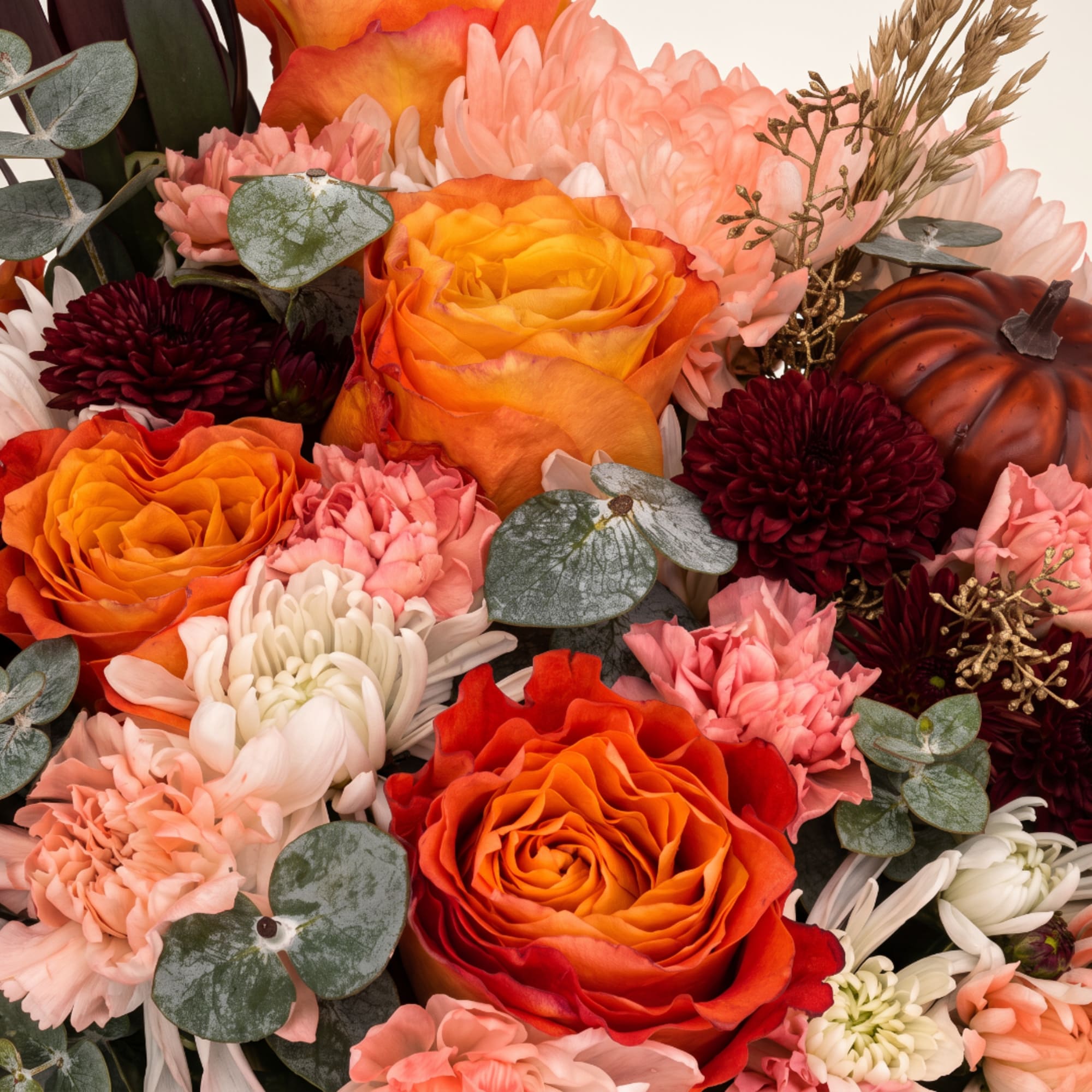 Orange and pink roses with chrysanthemums and eucalyptus in a close-up bouquet