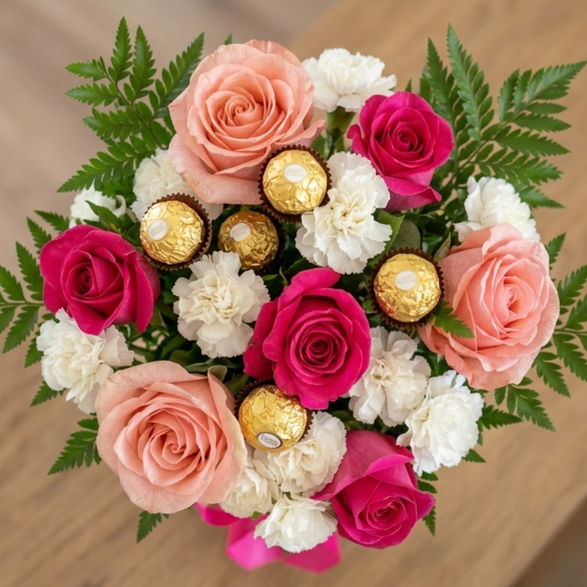 Bouquet of pink and peach roses with white carnations and gold chocolates