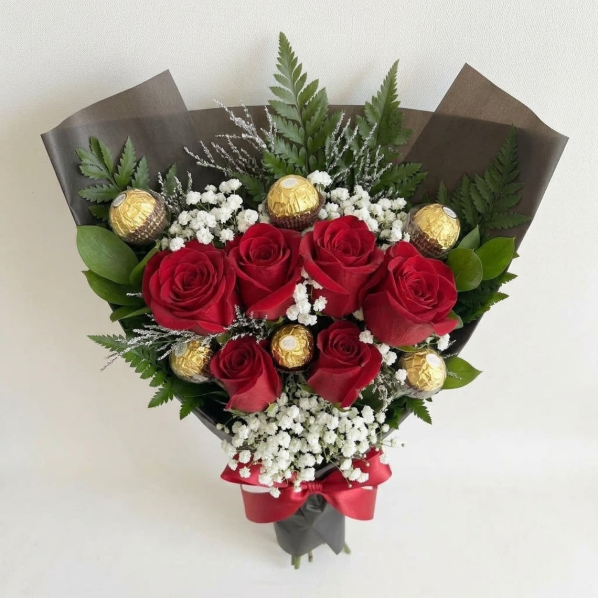Bouquet of red roses with gold-wrapped chocolates and white filler flowers