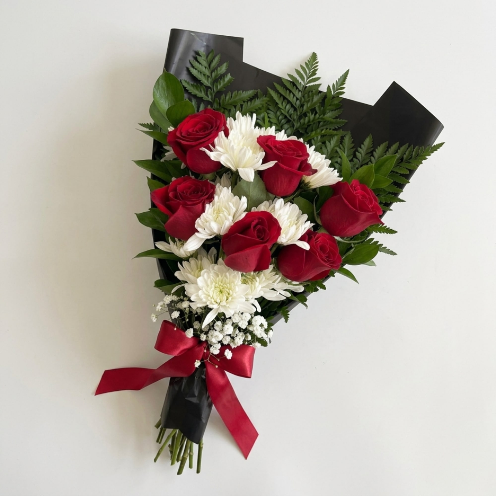 Bouquet of red roses and white chrysanthemums wrapped in black paper