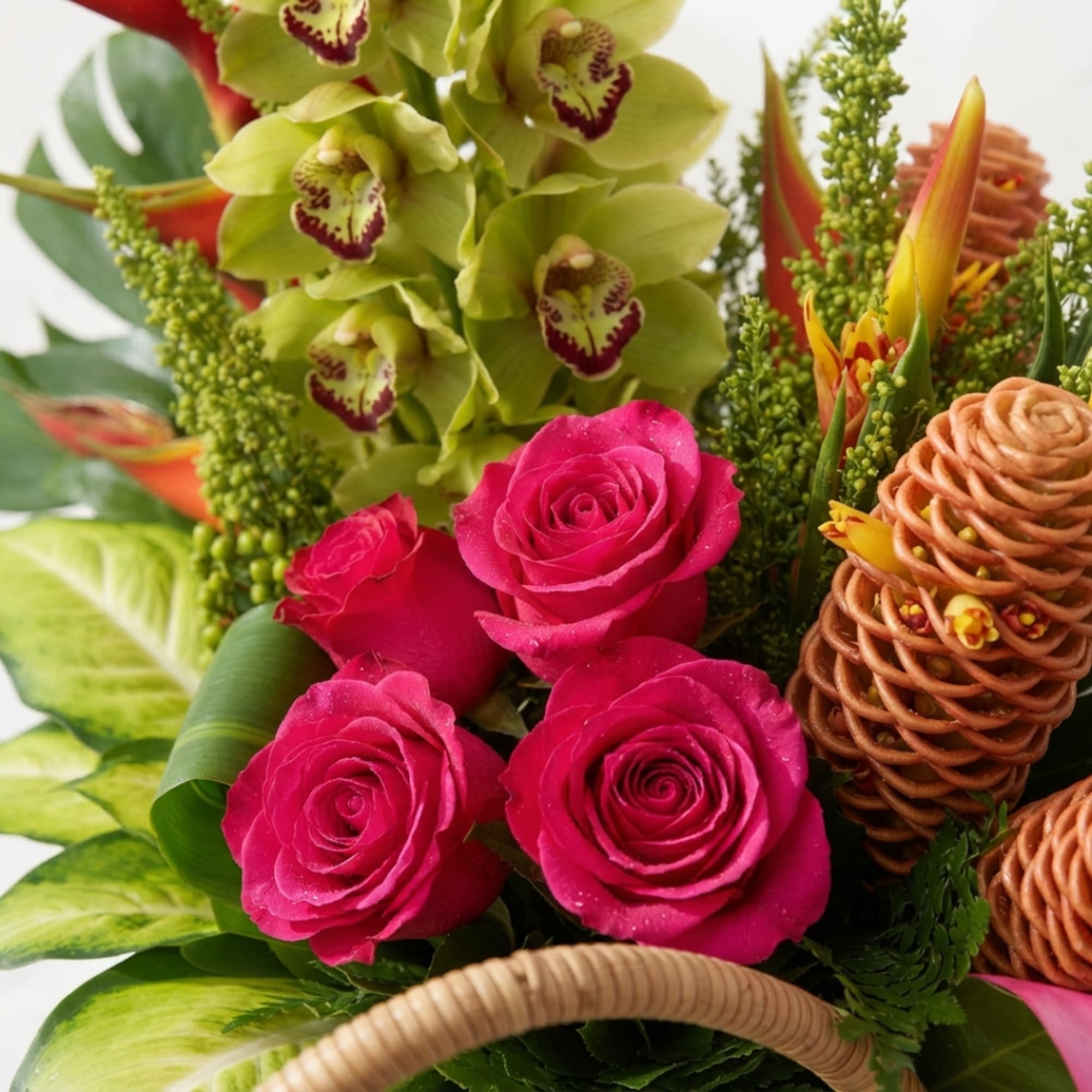Bright floral arrangement with pink roses, green orchids, and orange tropical blooms in a basket