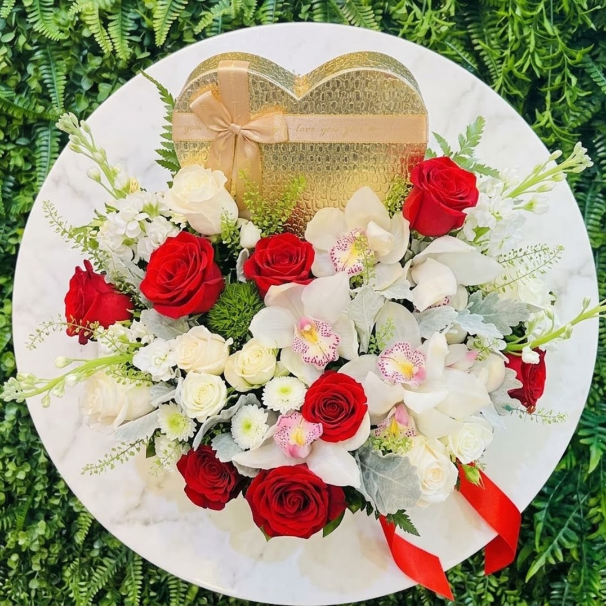 Red and white rose bouquet with orchids on a round white tray