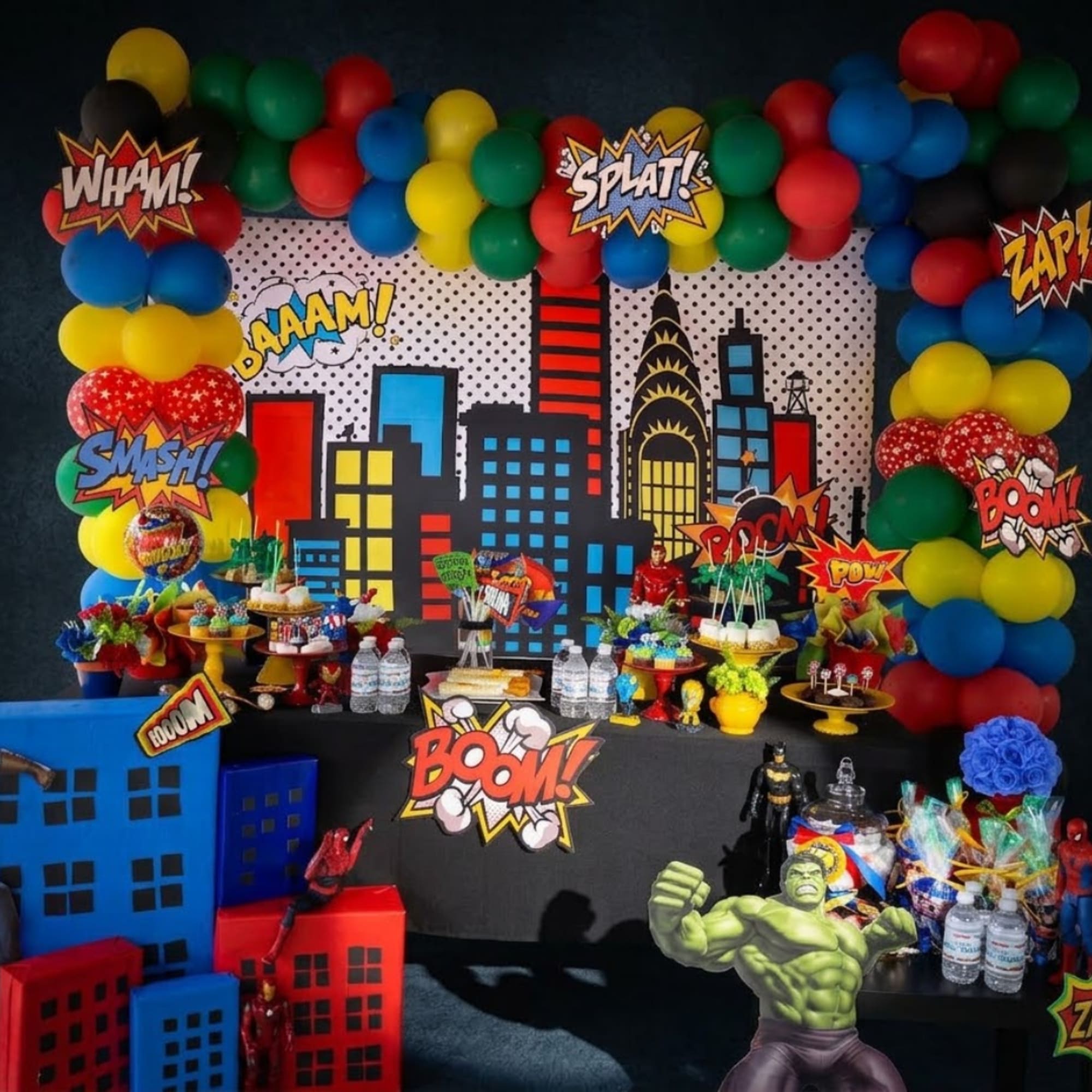 Superhero-themed party display with balloons, comic signs, and dessert tables, photo 2 of 7