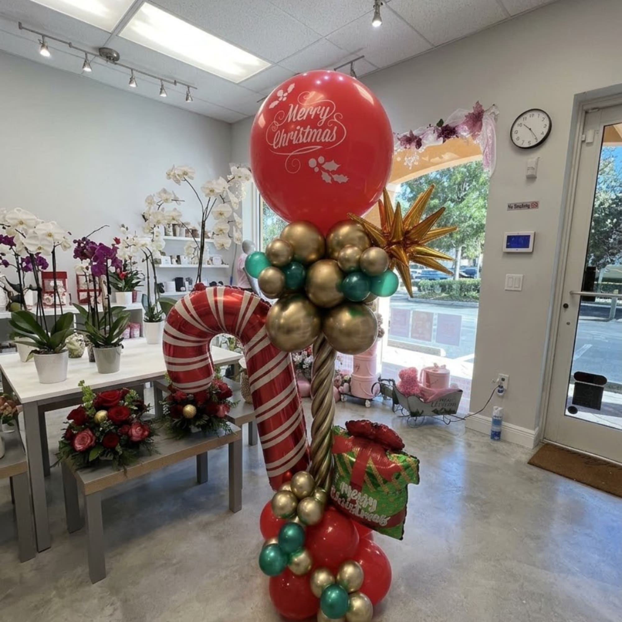 Christmas balloon display with a candy cane decoration and floral arrangements in a shop