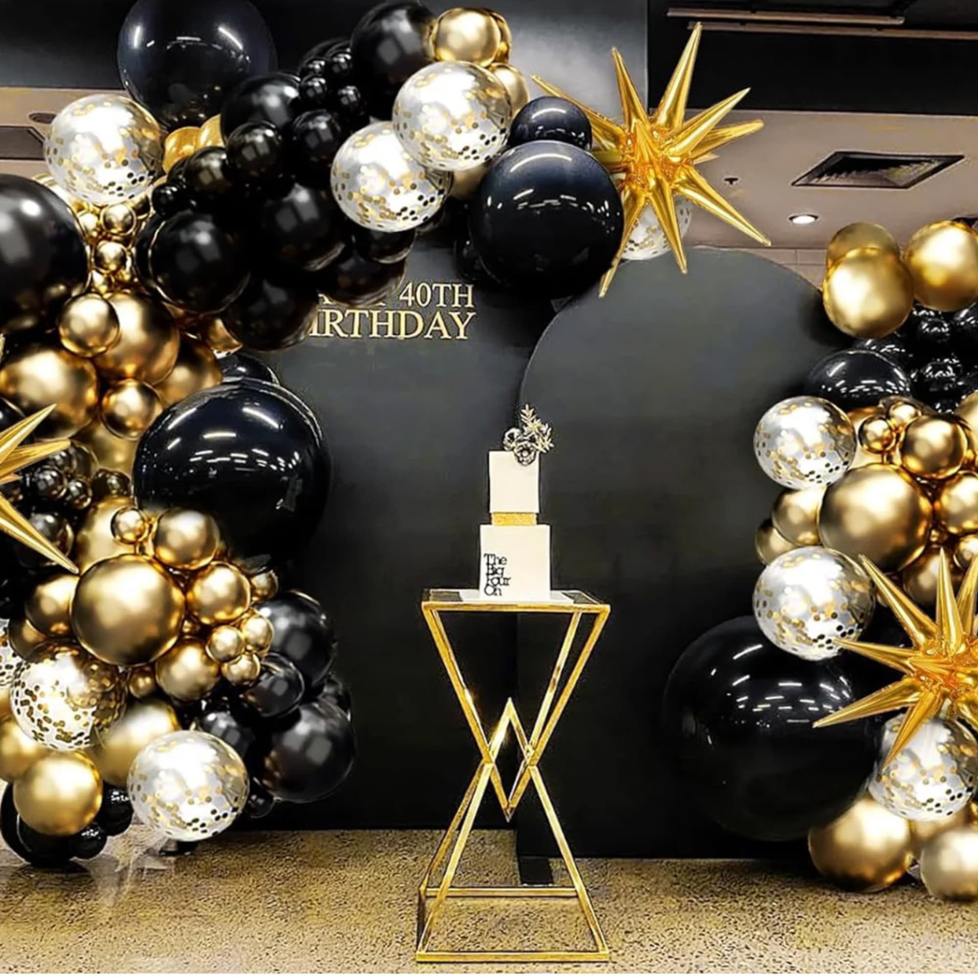 Black, gold, and white balloon arch around a 40th birthday display