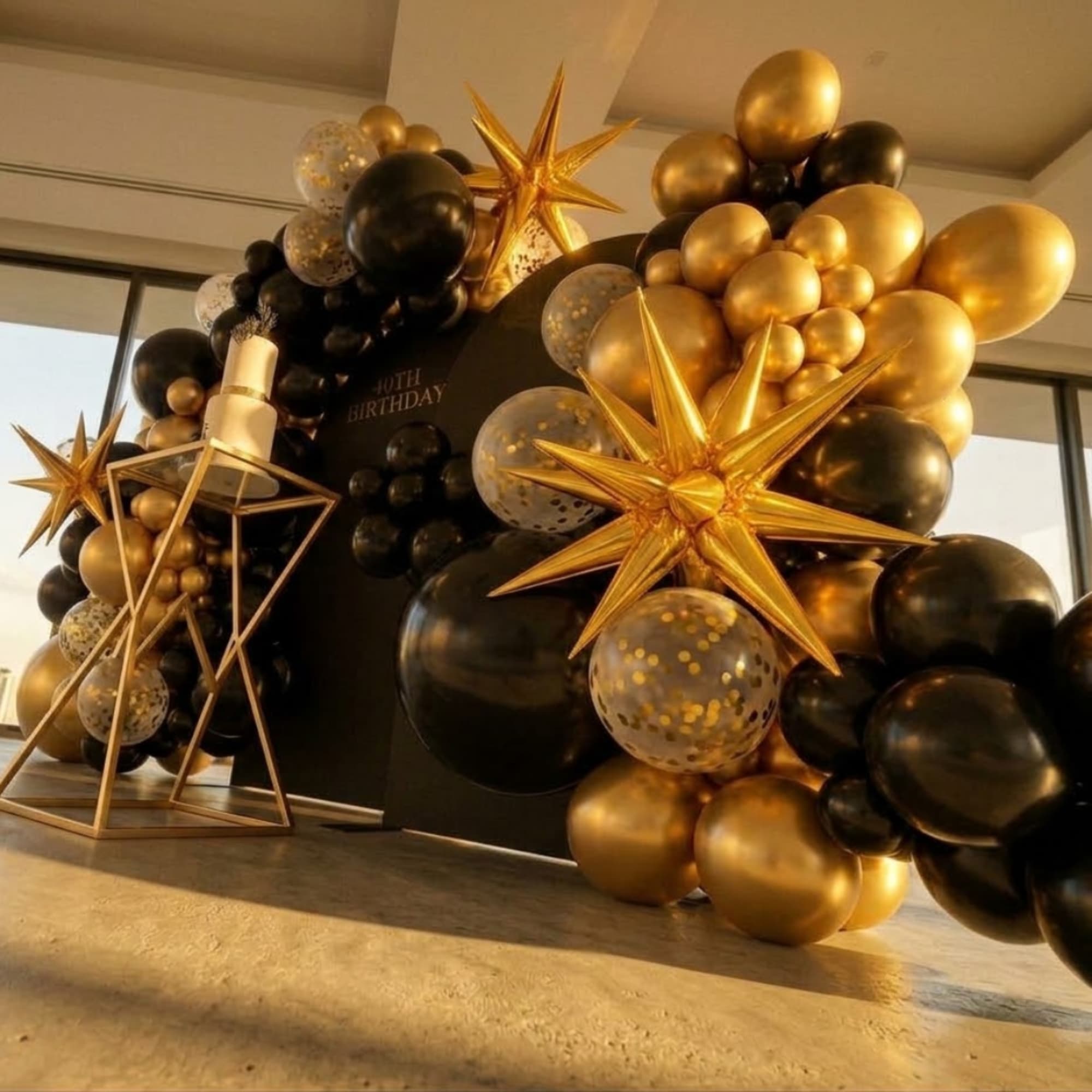 Black and gold birthday balloon display with star decorations