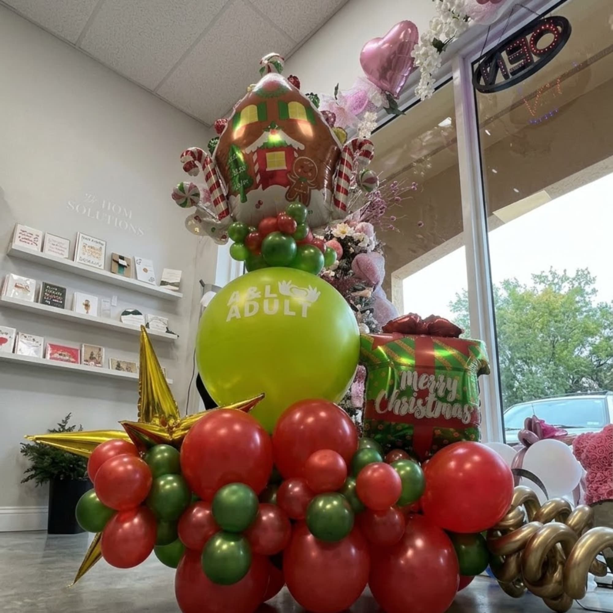 Christmas balloon display with a gingerbread house balloon and red and green balloons