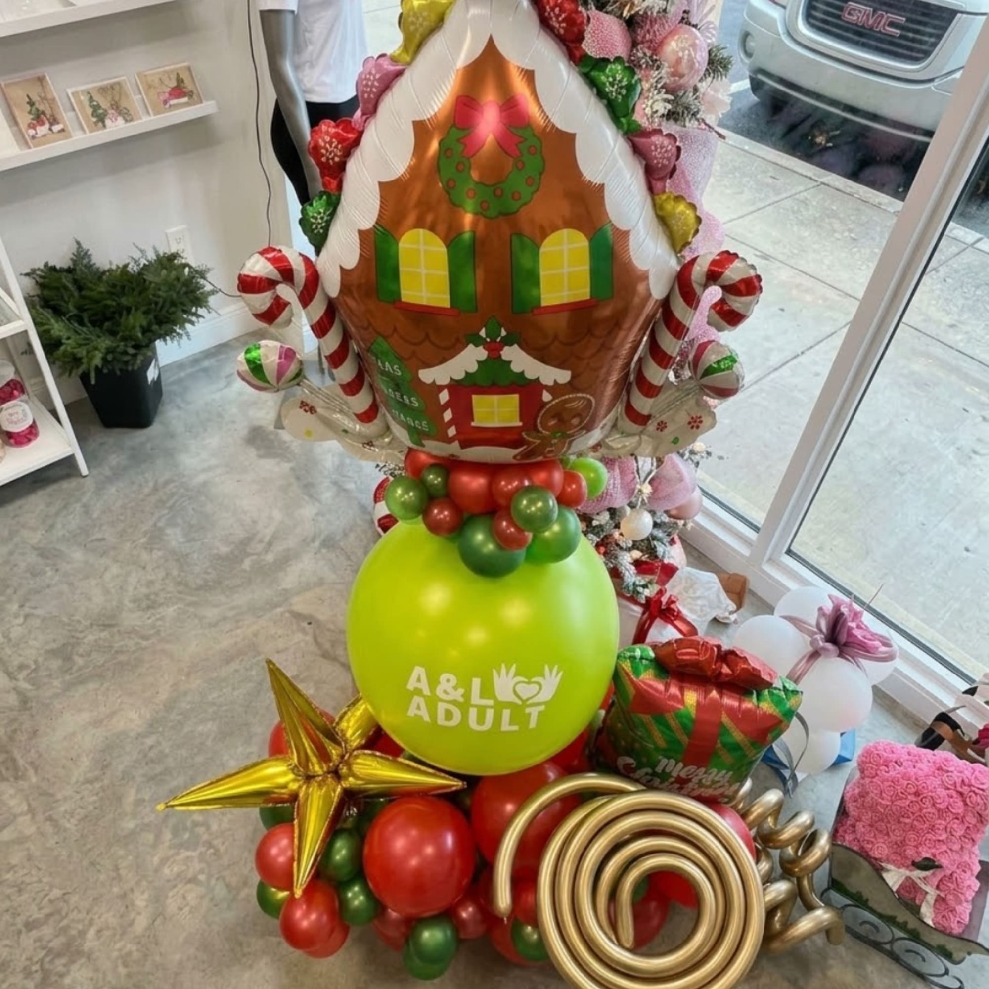 Christmas balloon display with a gingerbread house balloon and red, green, and gold balloons