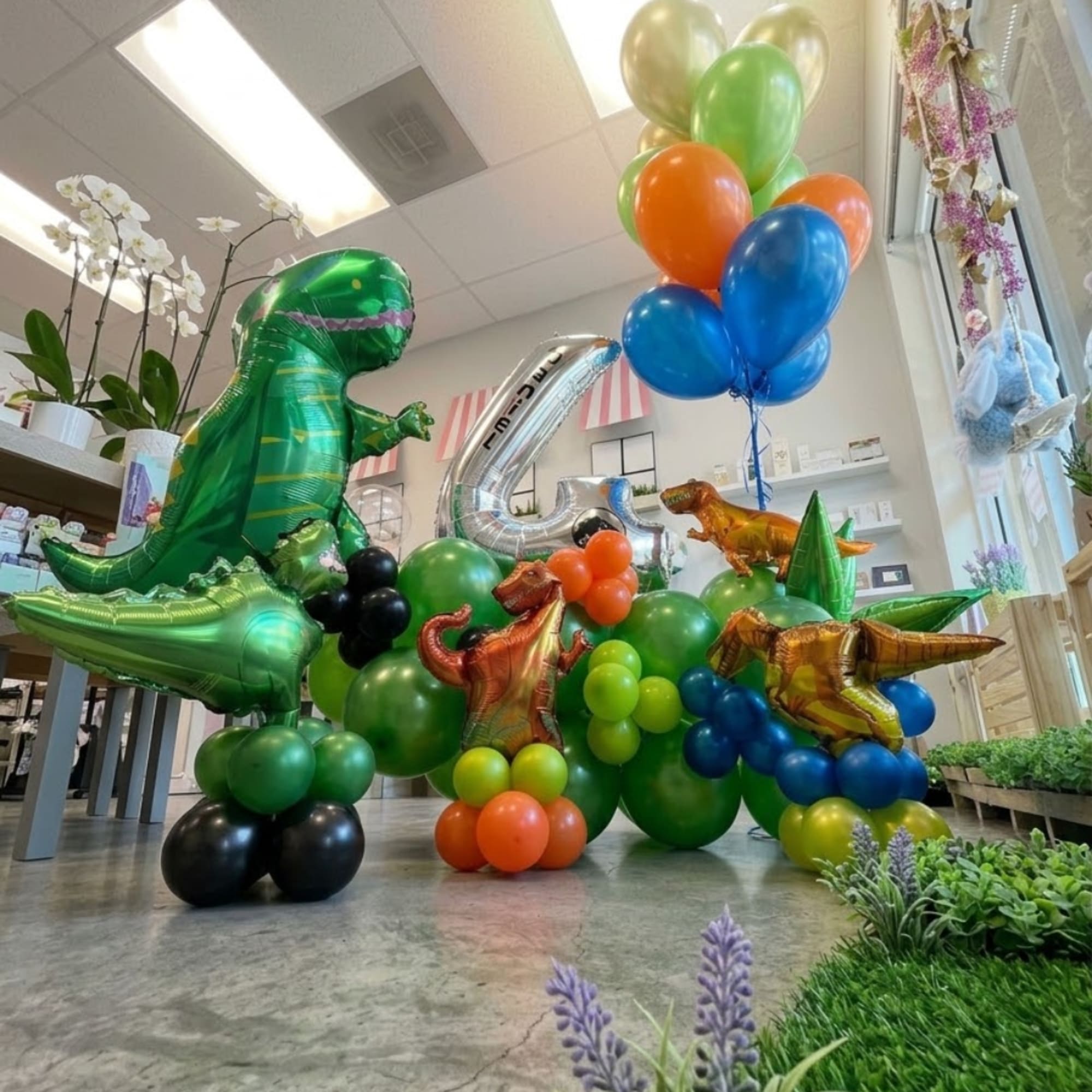 Dinosaur-shaped balloons and colorful balloon clusters in a shop interior
