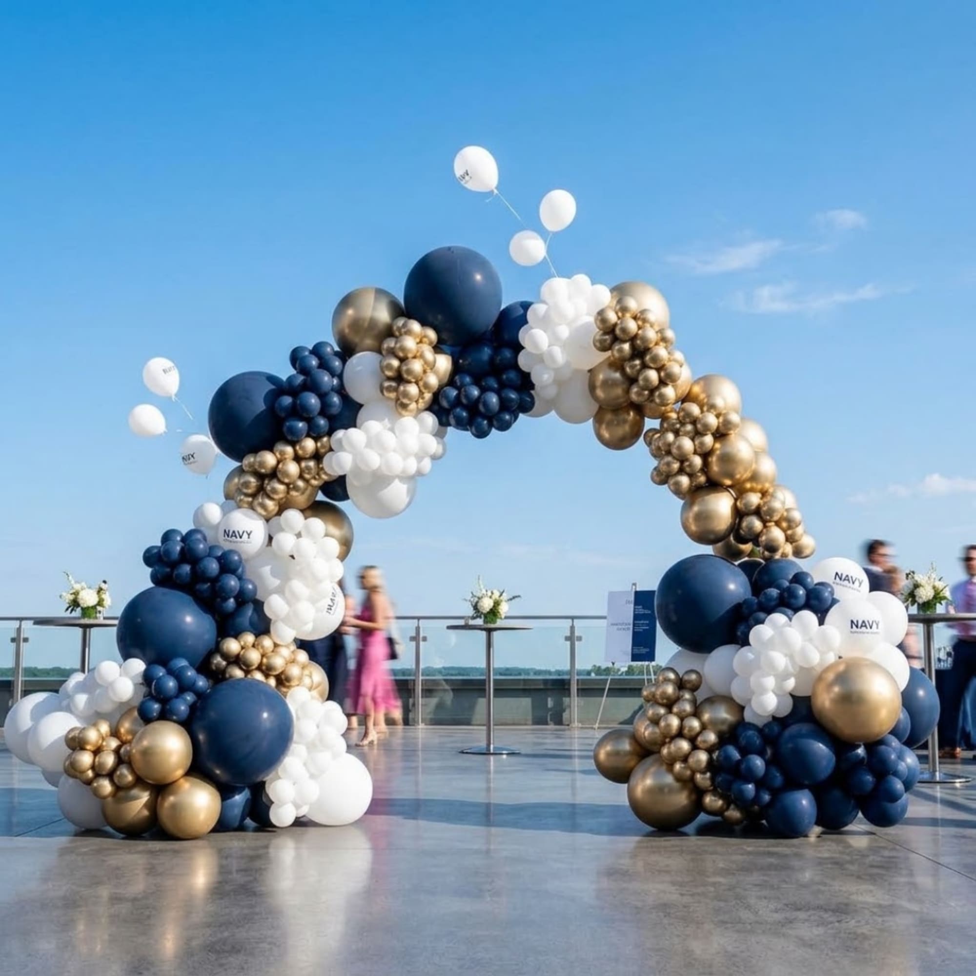 Navy, white, and gold balloon arch outdoors on a terrace