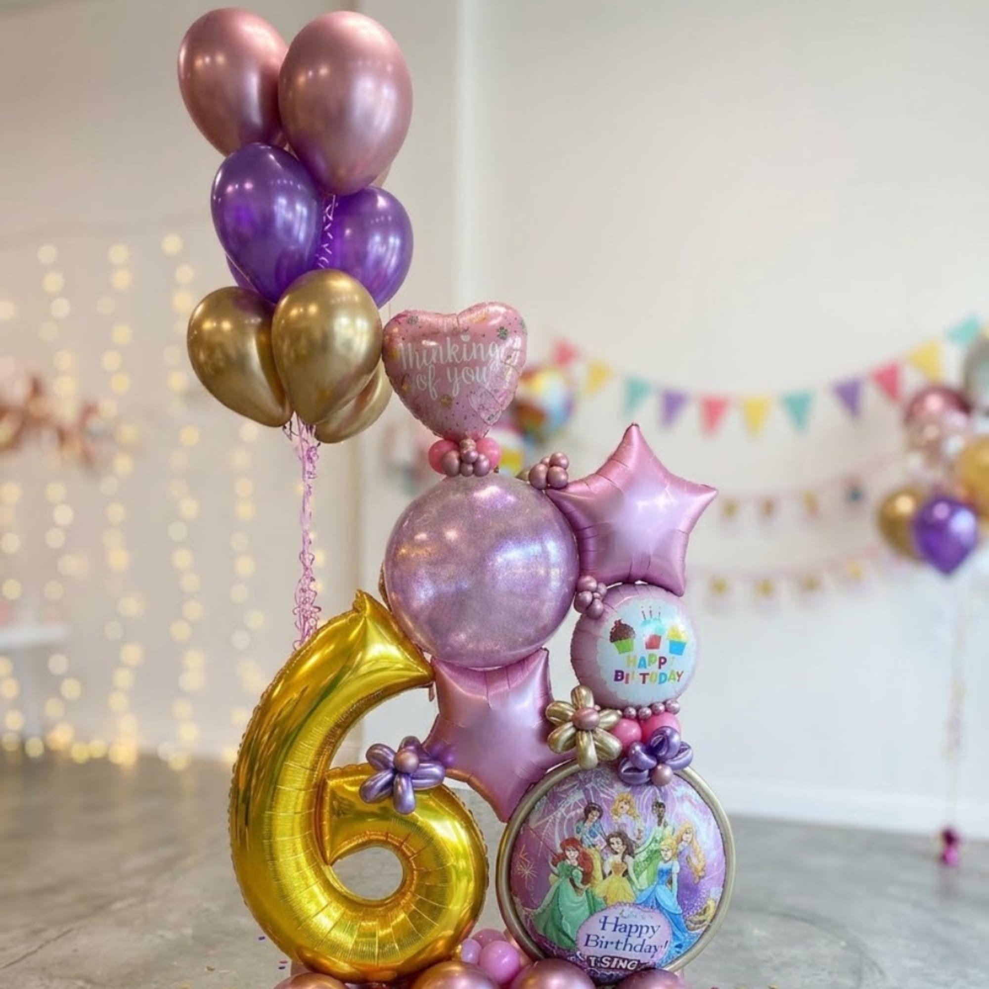Birthday balloon display with a gold number 6 and pink-purple balloons
