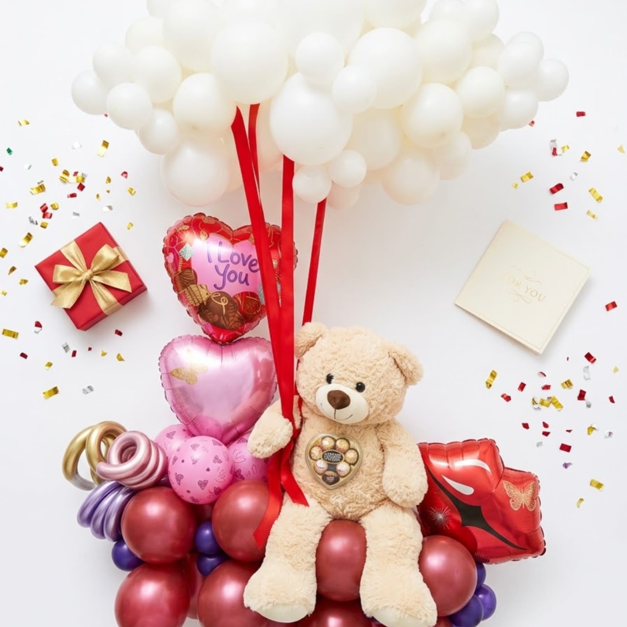 Balloon bouquet with a teddy bear, heart balloons, and gift boxes
