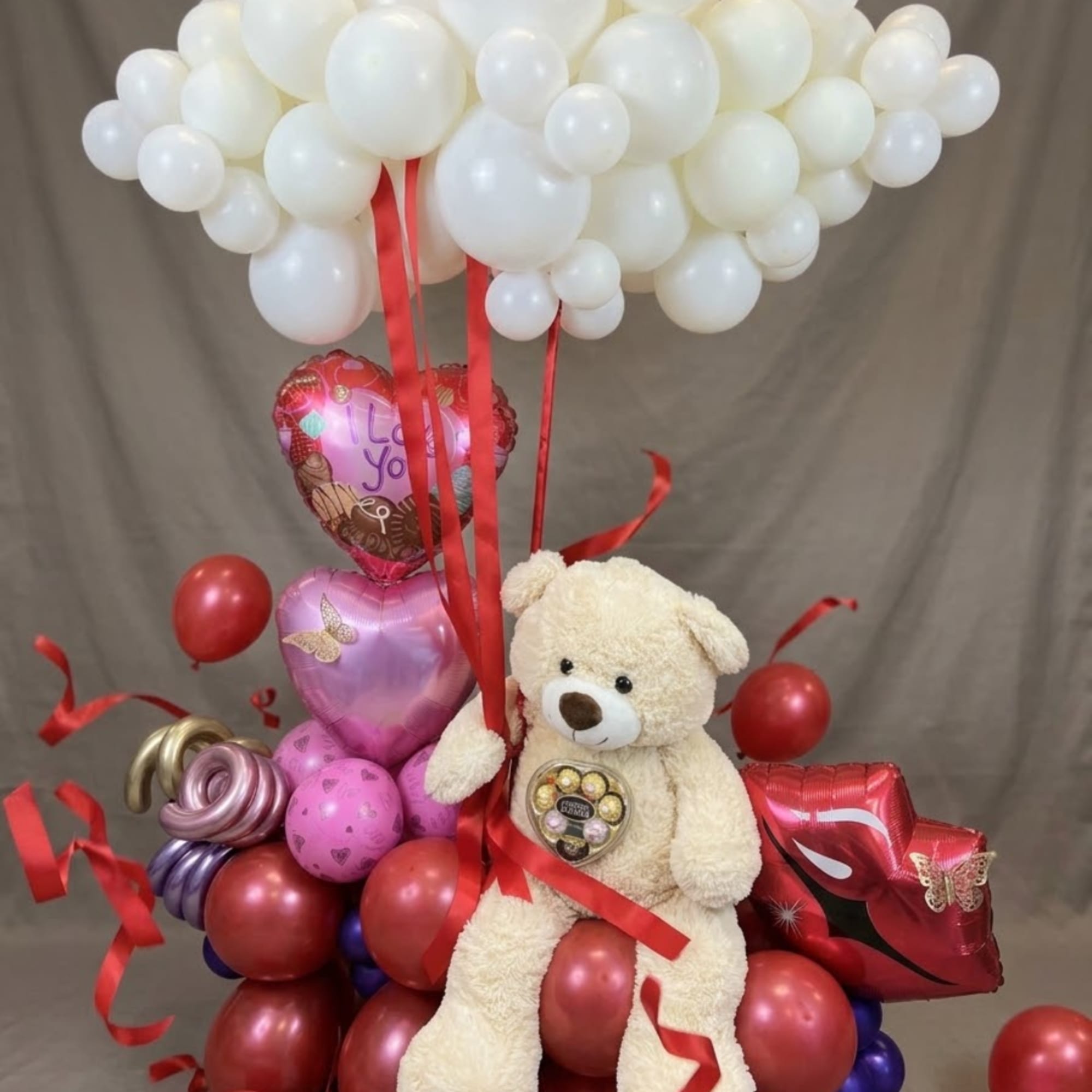 Teddy bear with heart balloons and a white balloon cloud