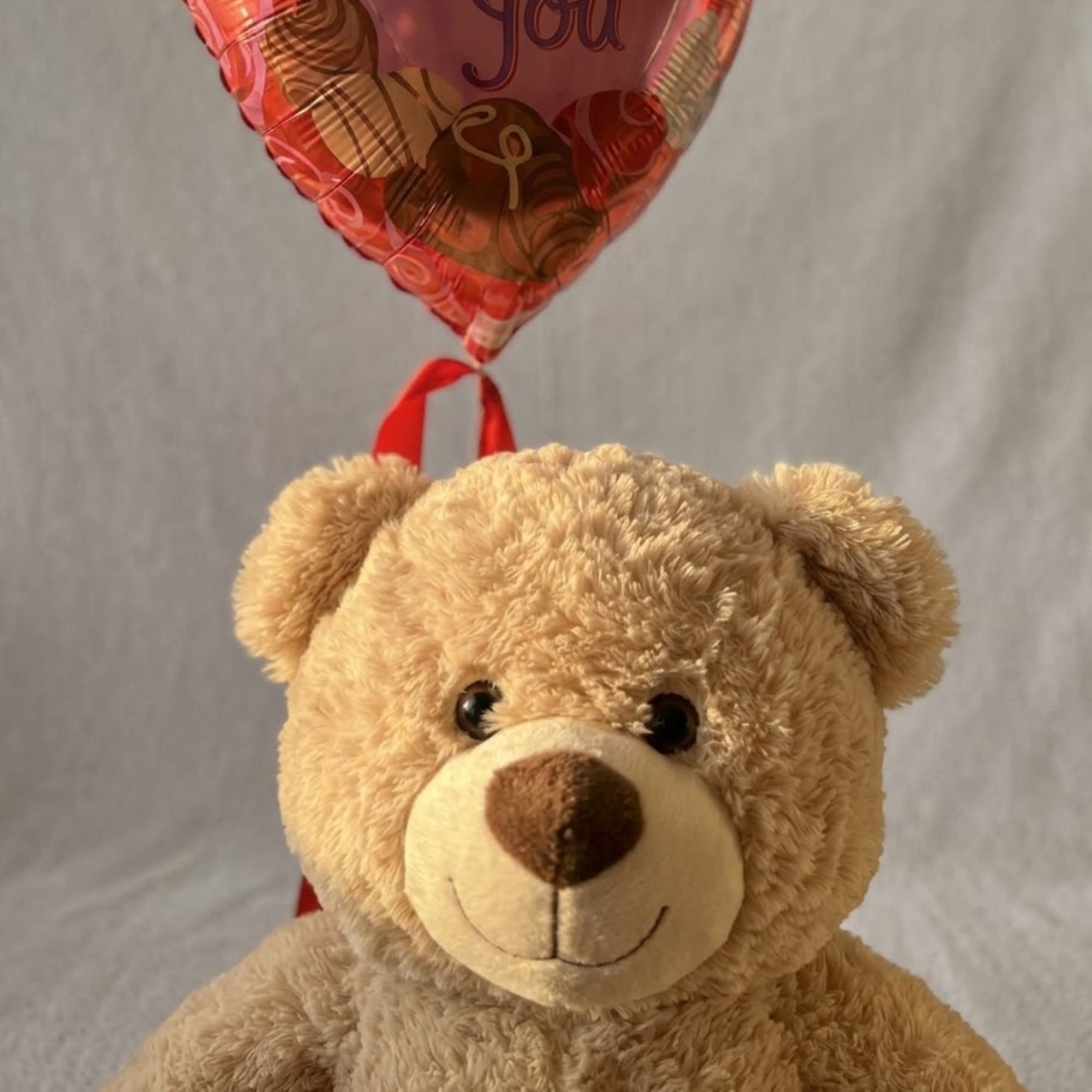 Teddy bear with a heart-shaped balloon above it