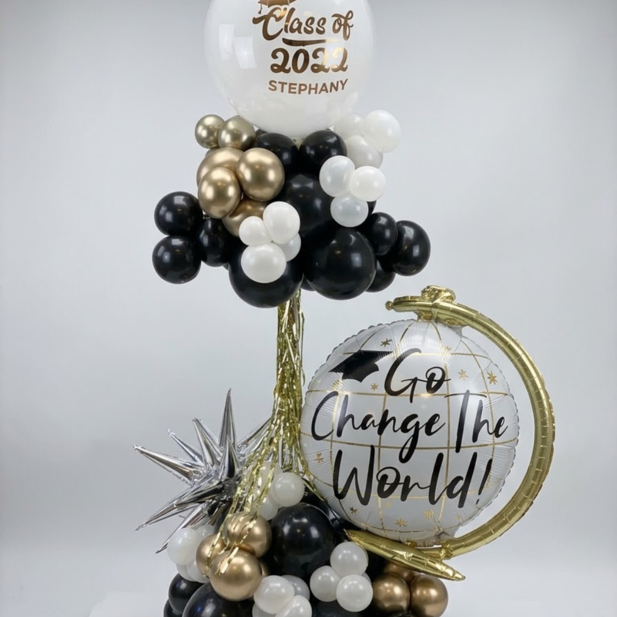 Graduation balloon arrangement with black, white, and gold balloons and two printed balloons
