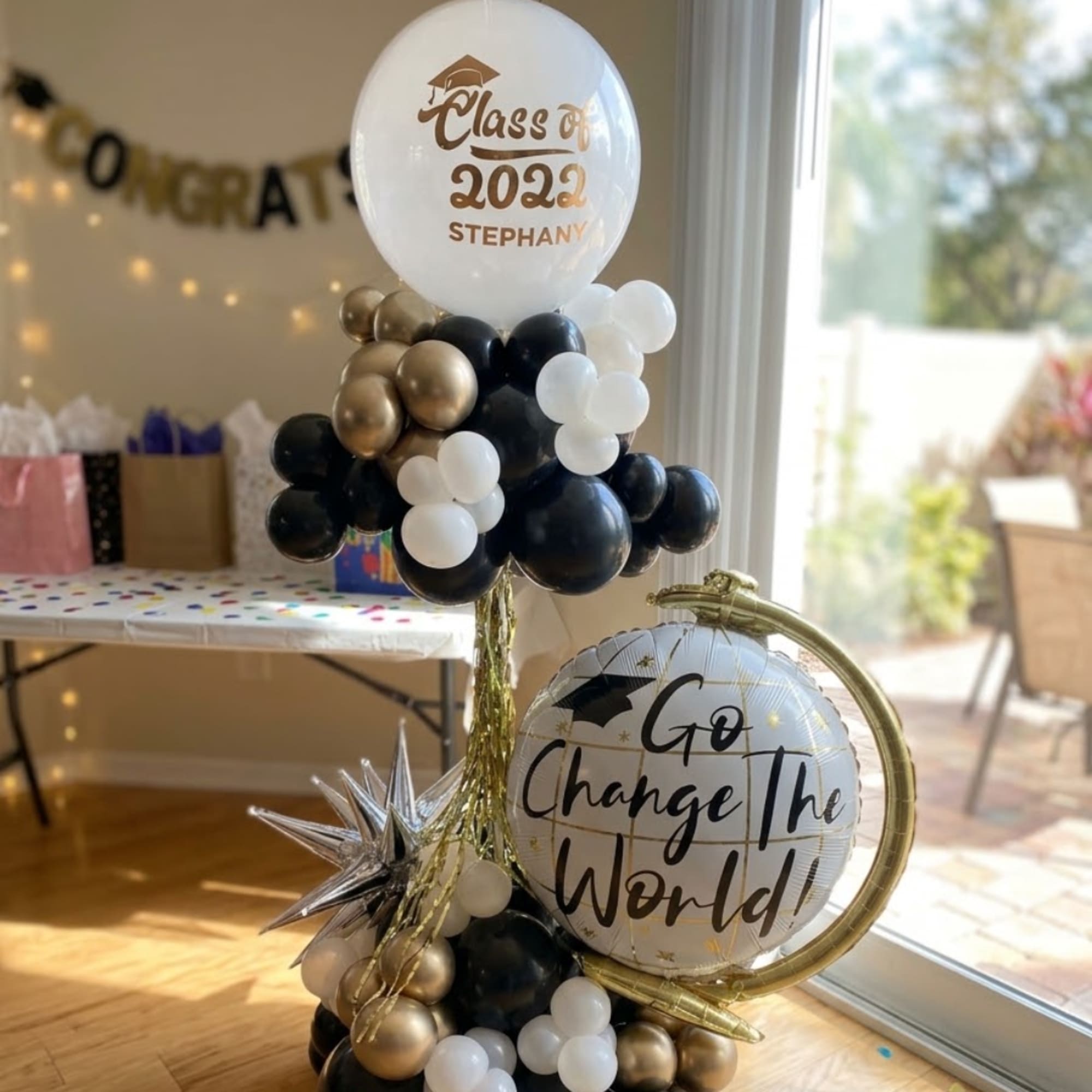 Graduation balloon display with black, gold, and white balloons and two printed balloons