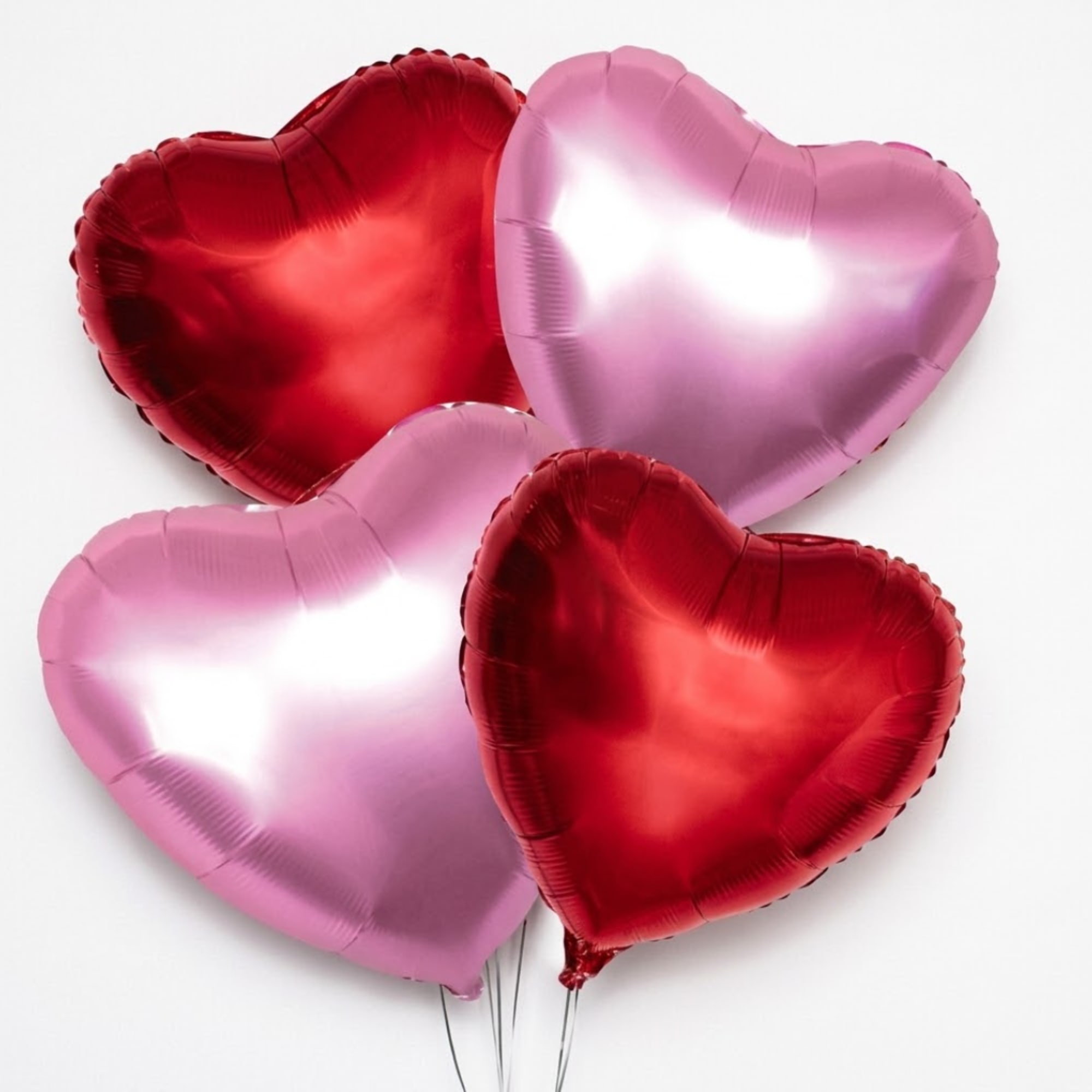 Heart-shaped red and pink balloons on a white background
