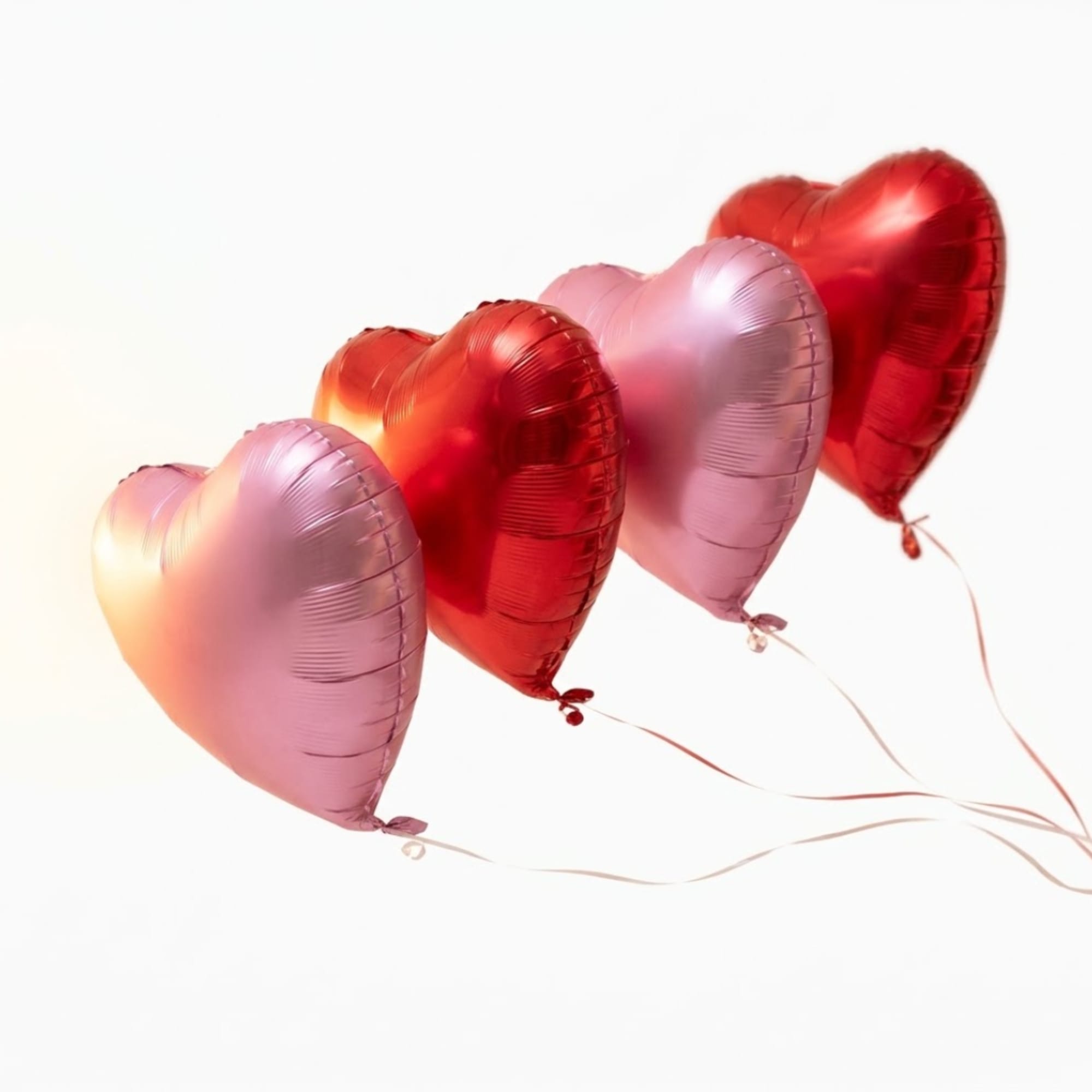 Heart-shaped pink and red balloons on a white background