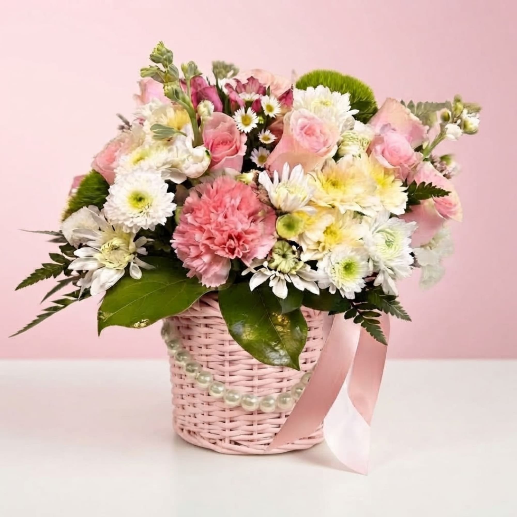 Pink and white mixed bouquet in a woven basket with a ribbon