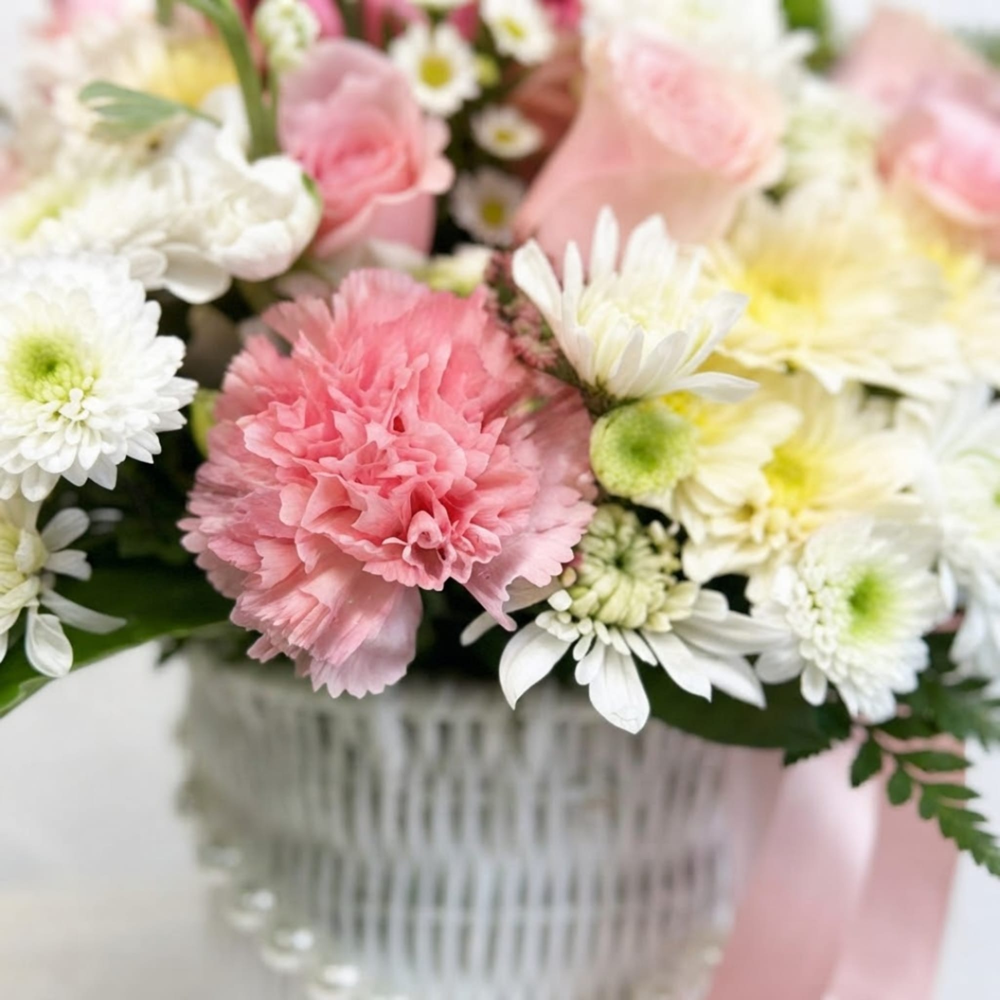 Pink carnations and white daisies in a clear glass vase