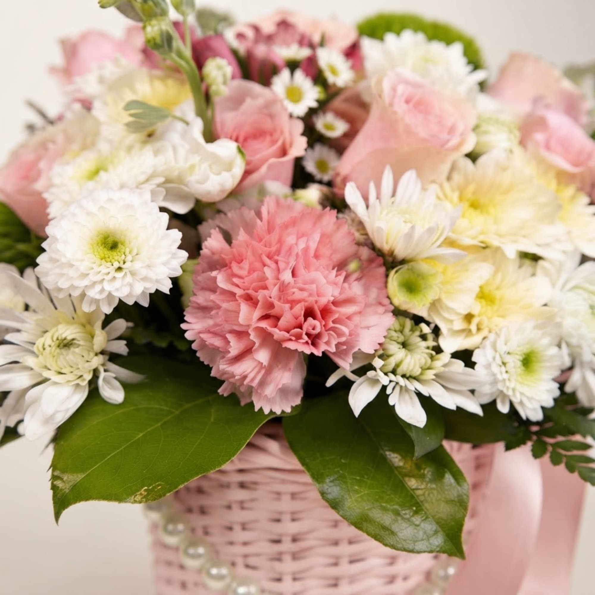 Pink and white flower arrangement in a pink basket