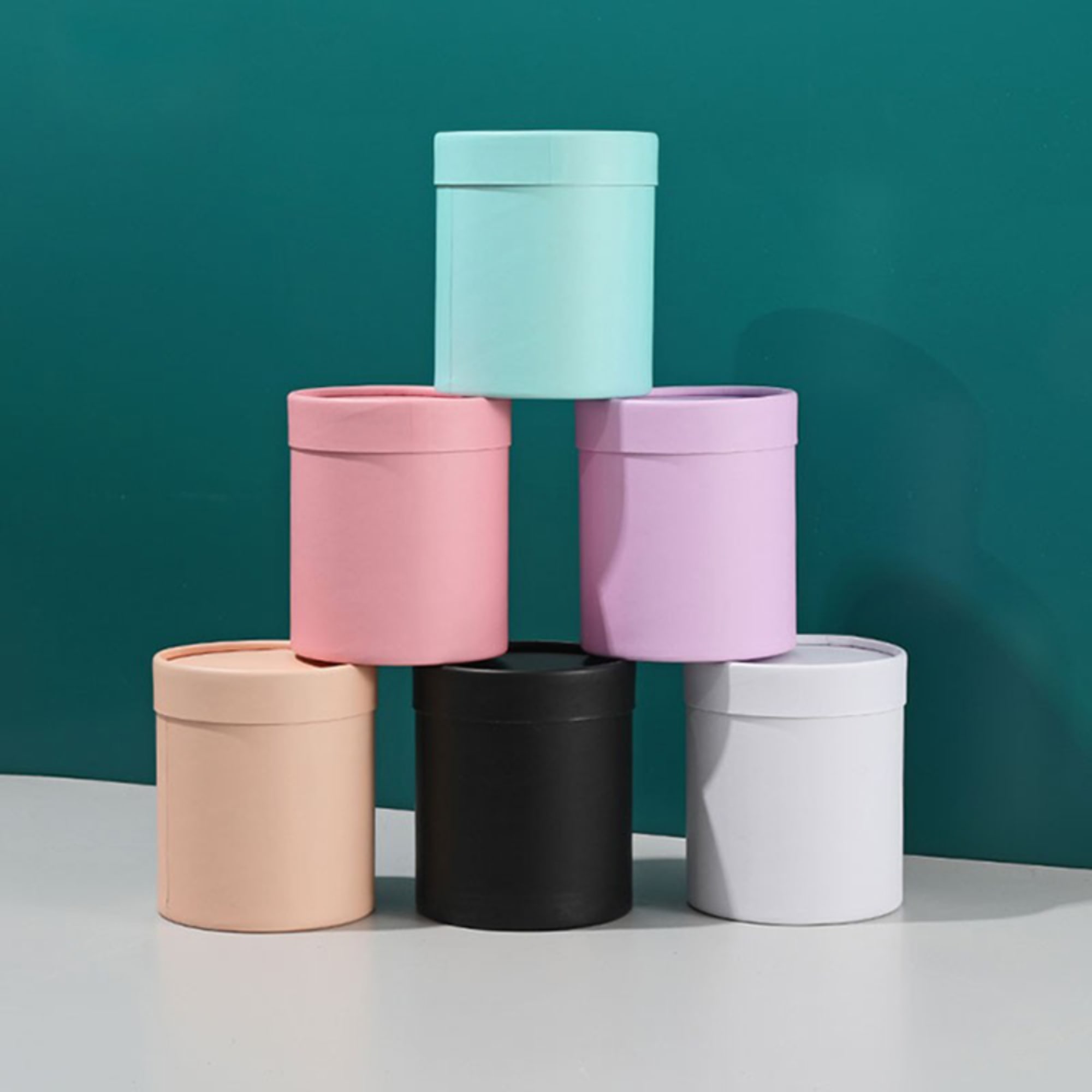 Stacked pastel round gift boxes on a teal background
