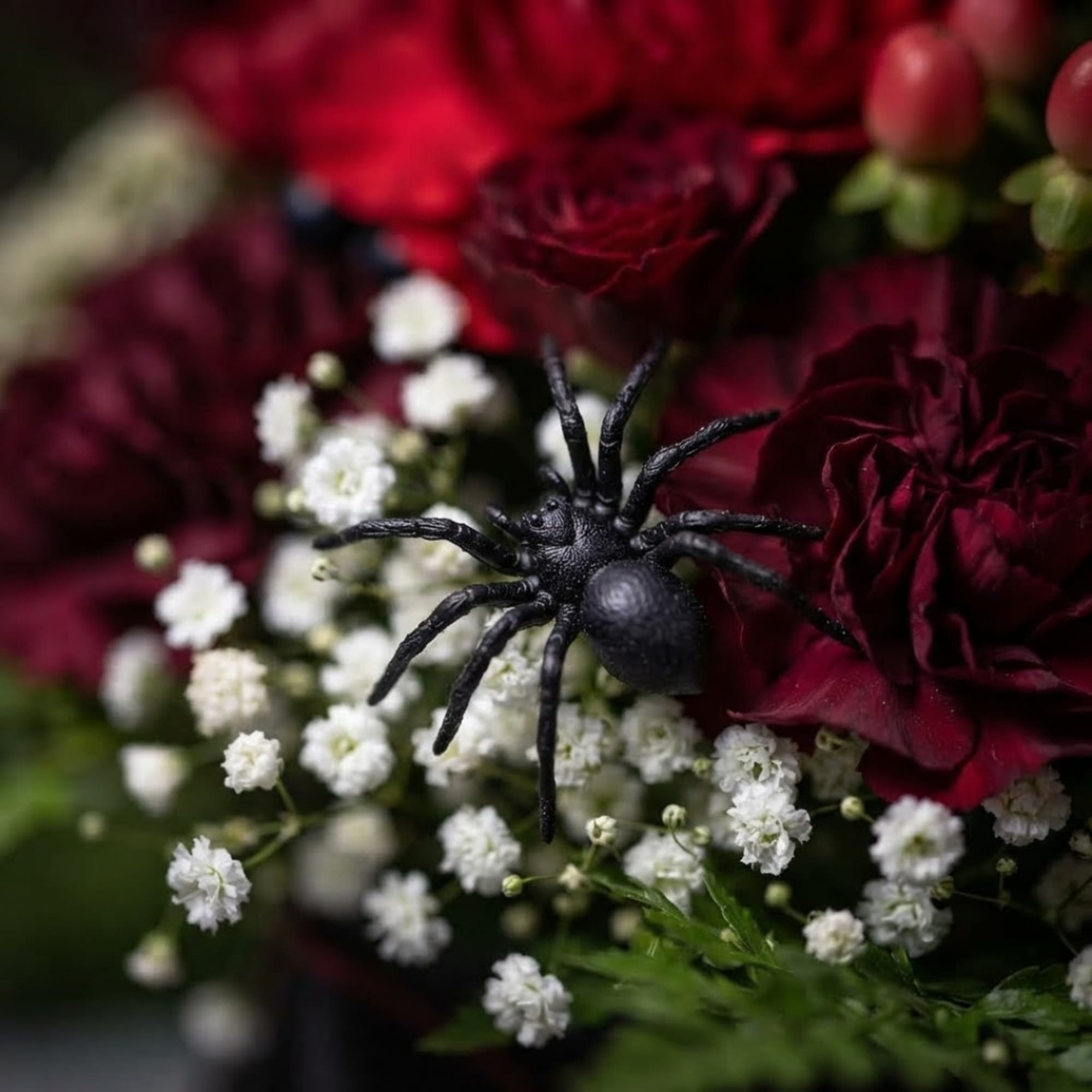 Dark red flowers with white filler and a black spider decoration