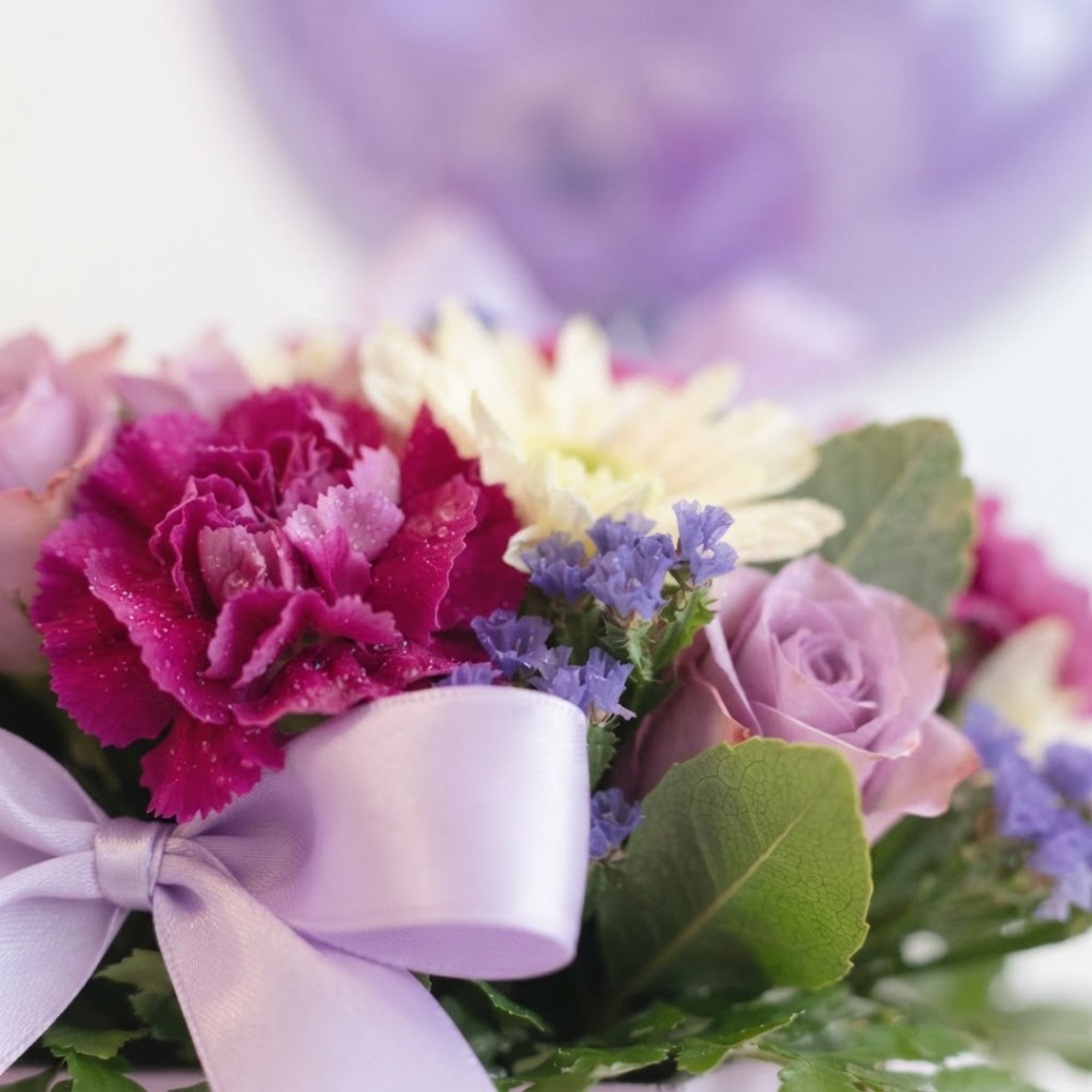 Pink and lavender bouquet with carnations, roses, and a ribbon bow