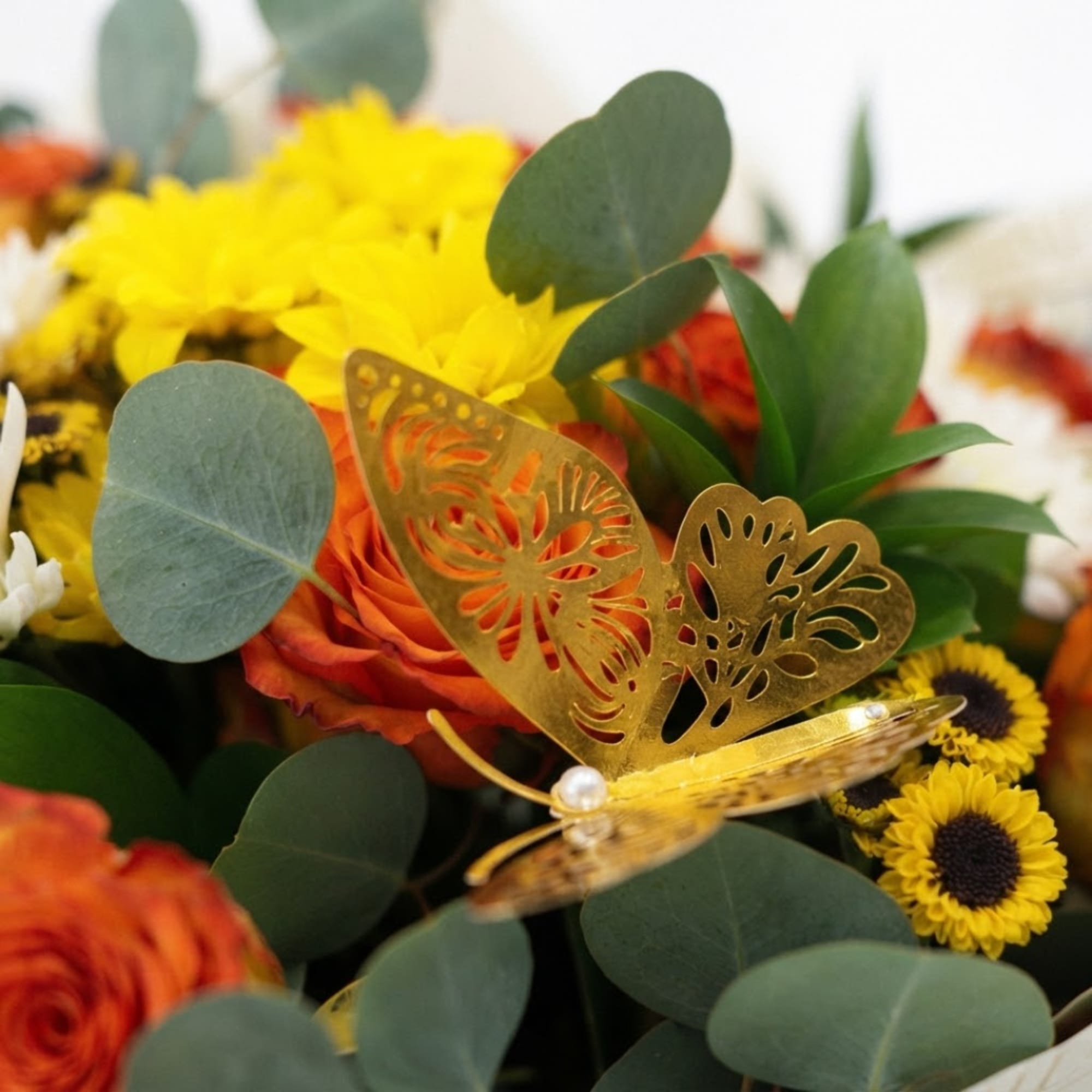Mixed bouquet with yellow and orange flowers and a gold butterfly pick