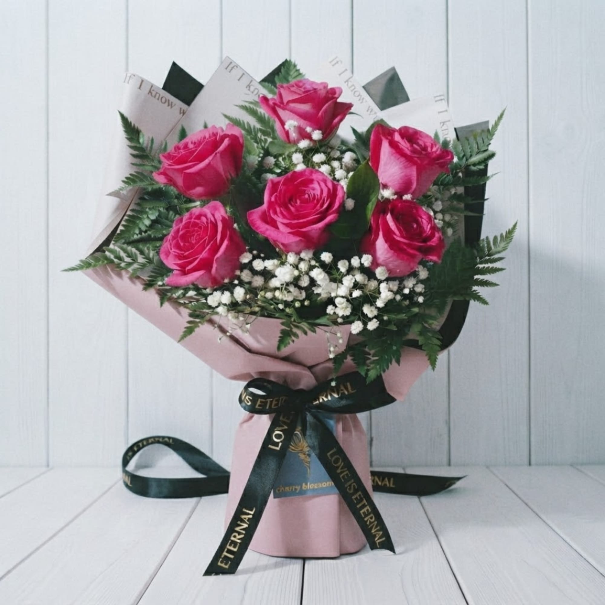 Pink rose bouquet with baby's breath in pink wrap and black ribbon