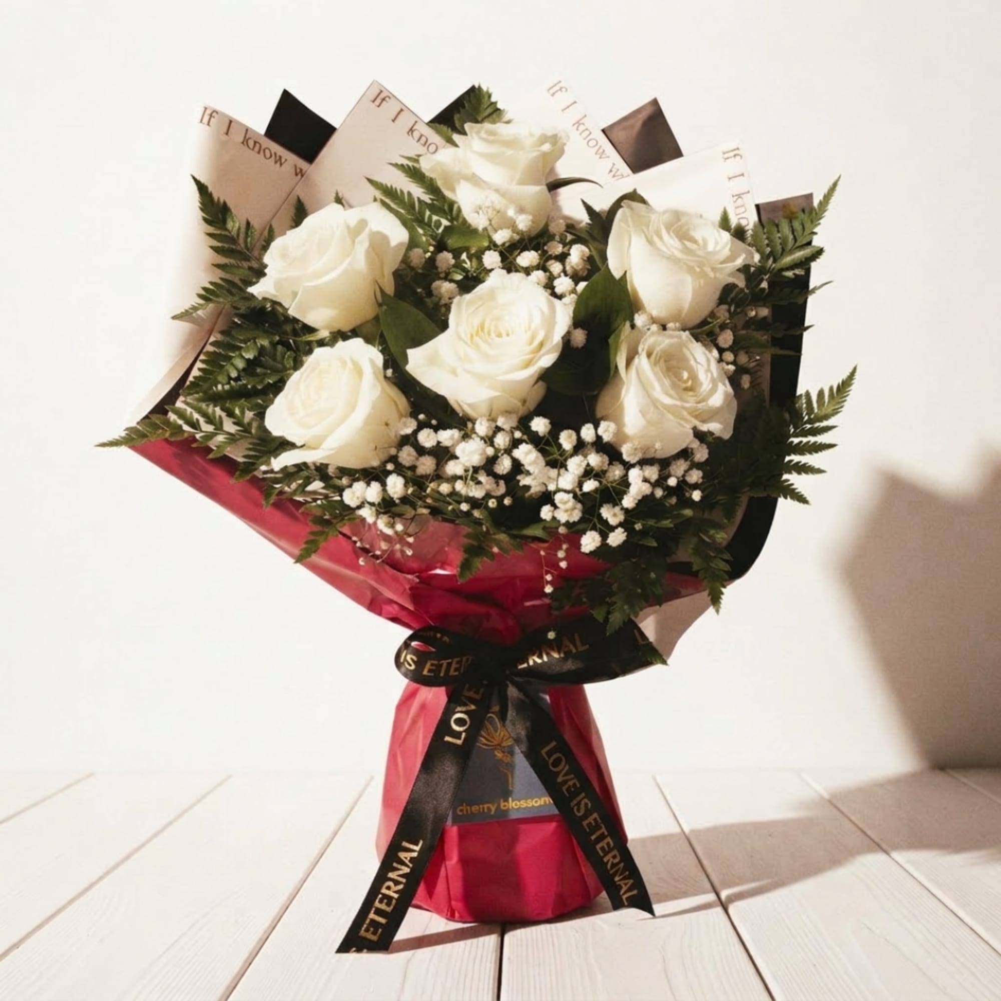 Bouquet of white roses with baby's breath in pink wrap